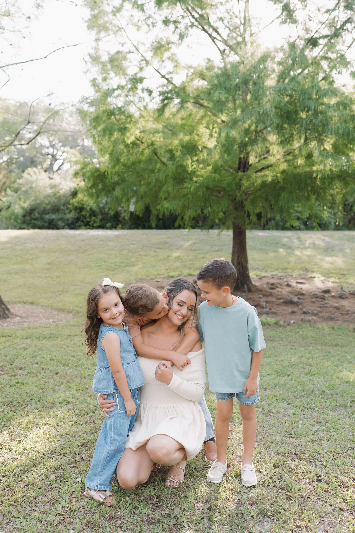An intimate family group photo under a shady tree in a park setting.