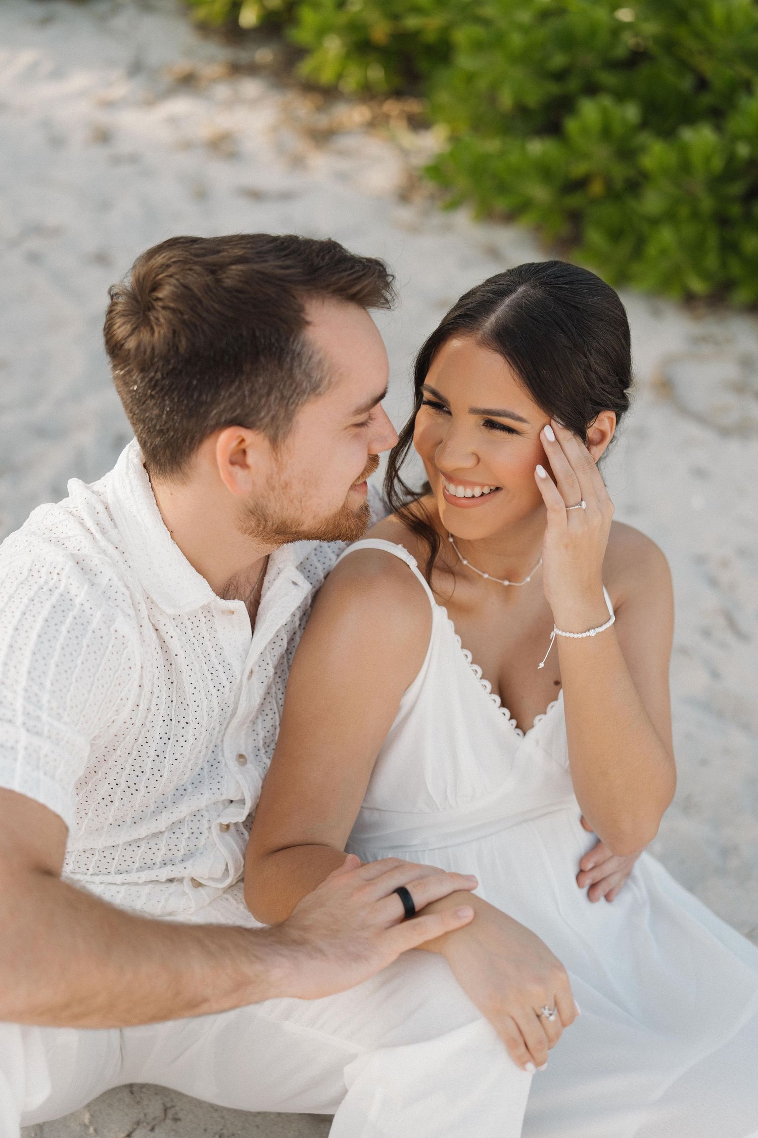 Intimate beach wedding photos showing tender moments between newlyweds on white sand.