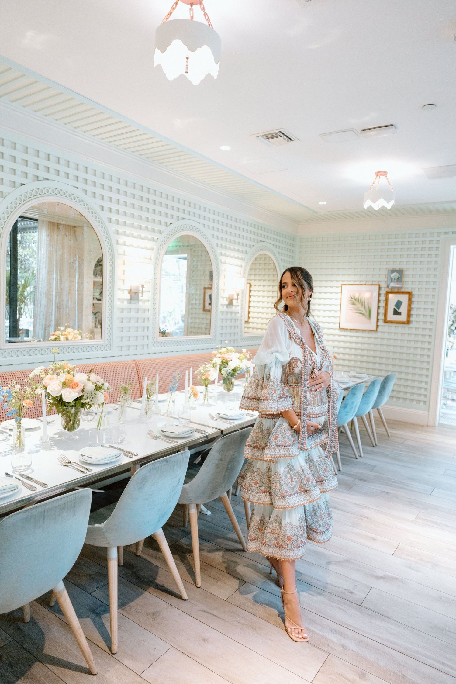 Elegant dining room with mint green wallpaper, blue velvet chairs, and floral centerpieces set for a special occasion.