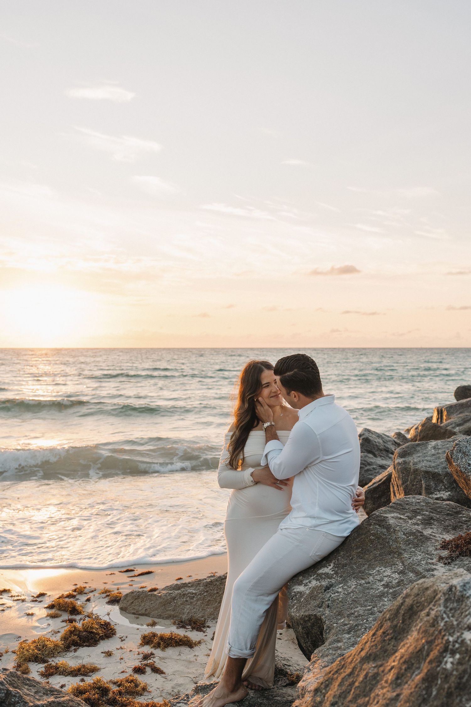 A romantic sunset moment on rocky coastal cliffs overlooking the ocean.
