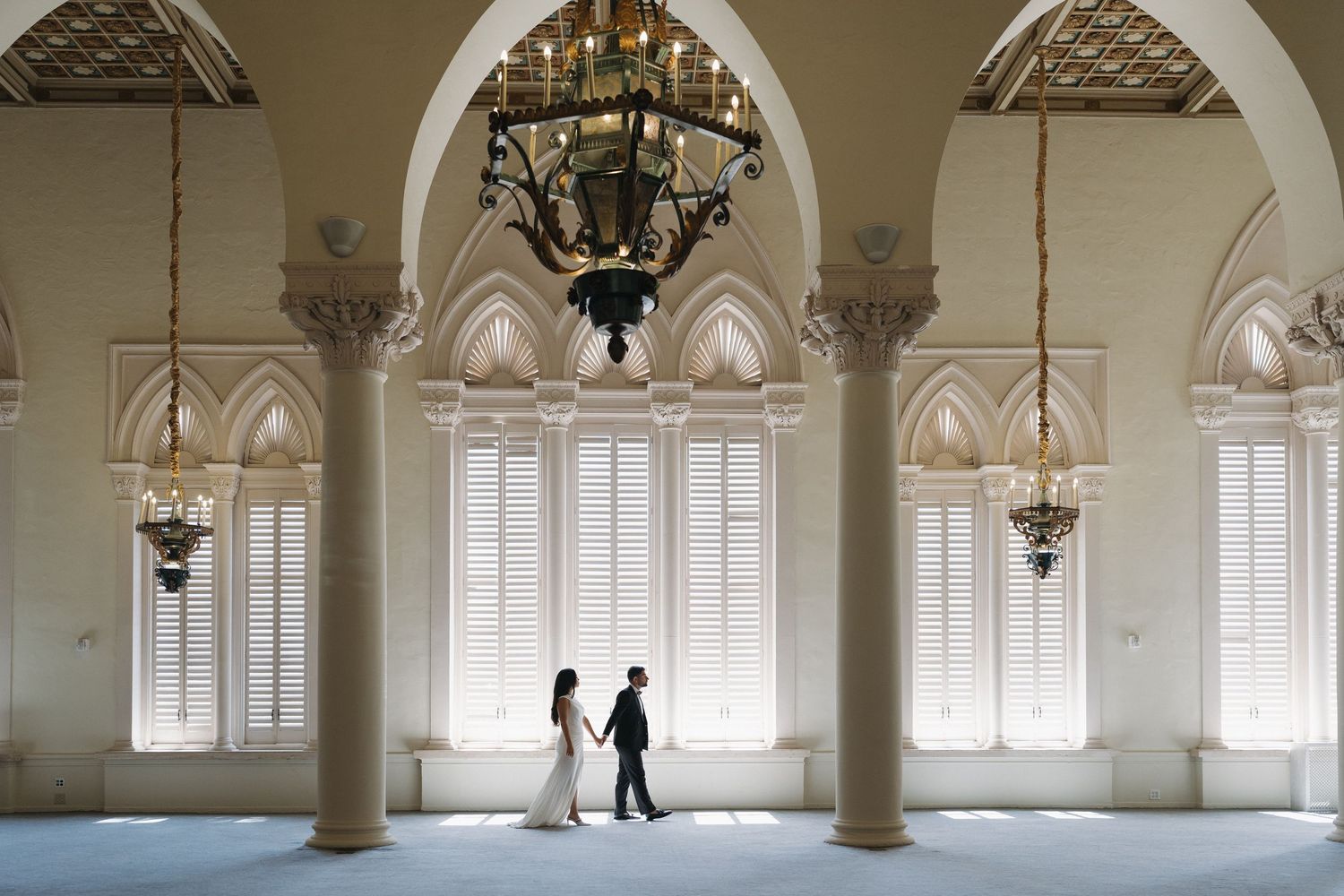 An elegant hallway with arched windows and columns creates a dramatic indoor setting.