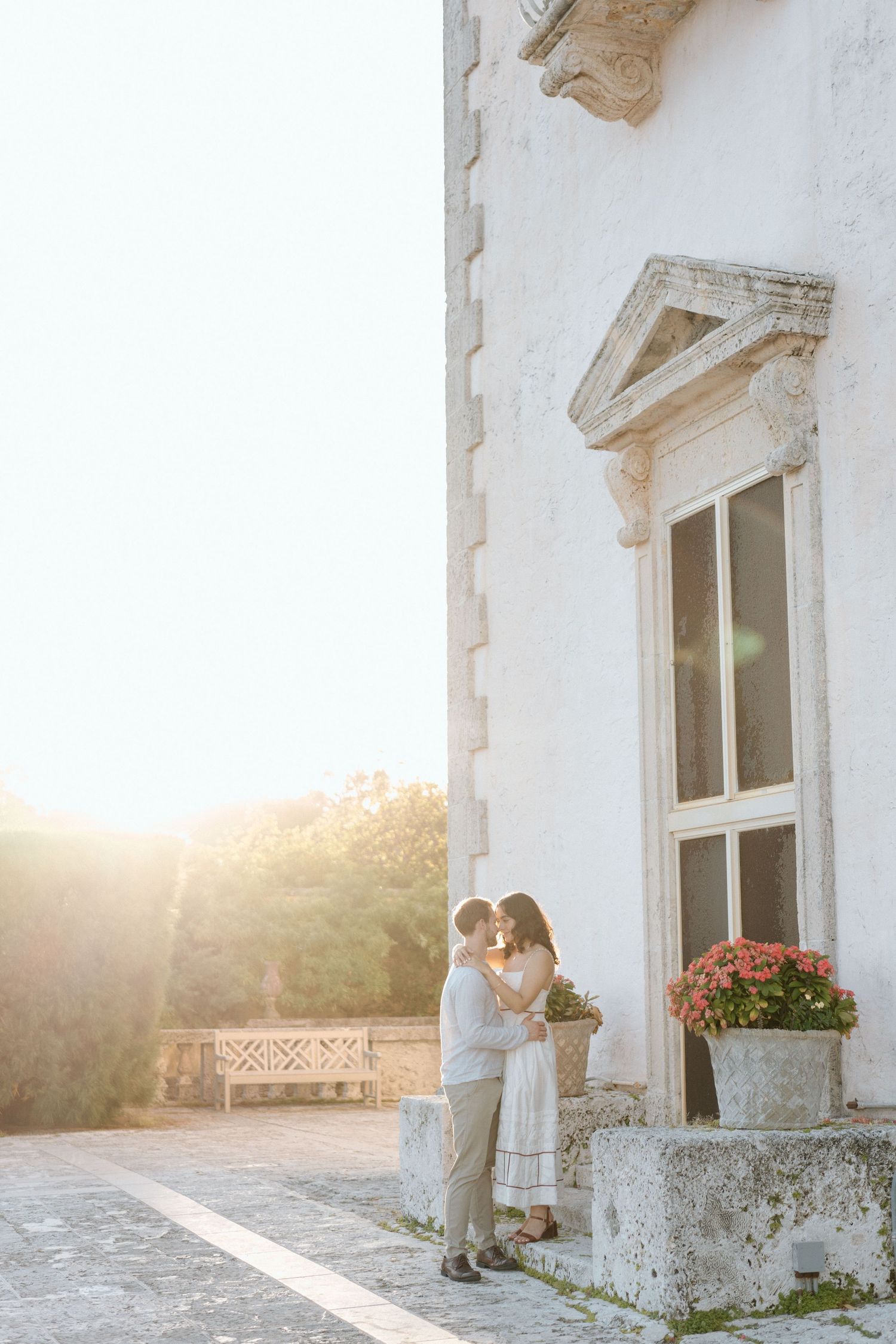 Romantic sunset moment against white stone architecture with blooming flowers.