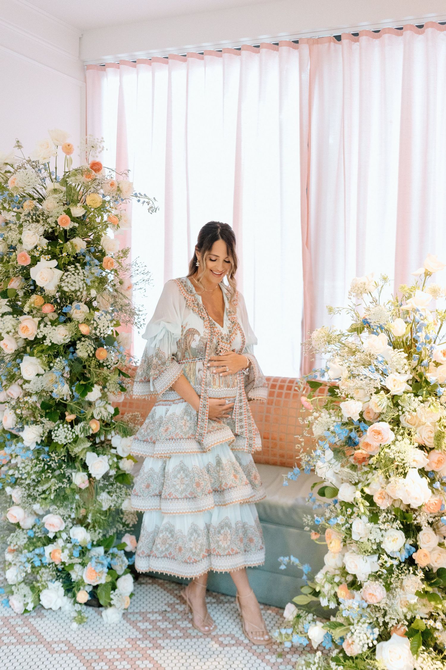 Romantic floral arrangements with white and peach blooms frame a decorated space with sheer curtains.