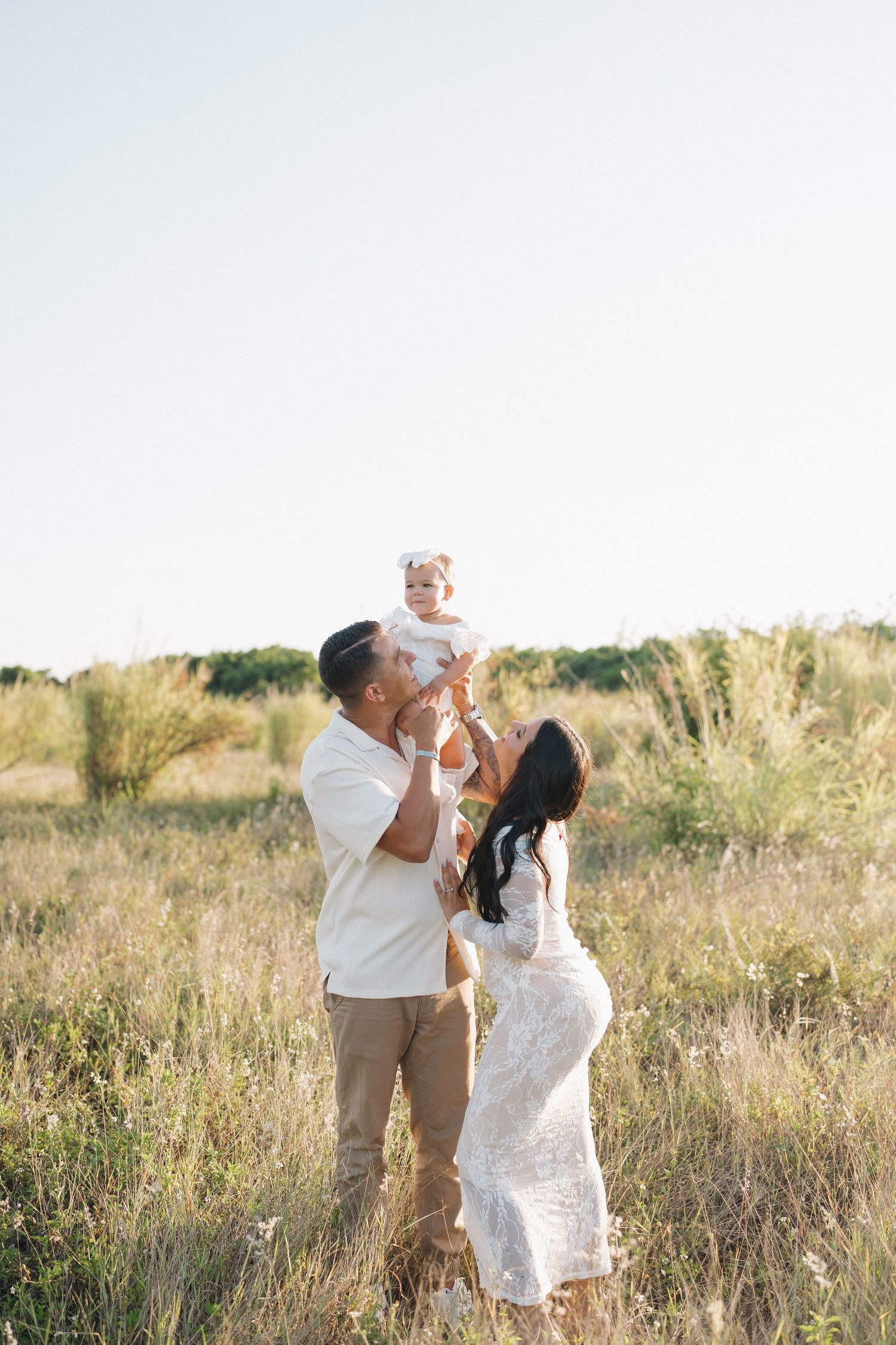 Family portrait in golden field during sunset with tall grass.