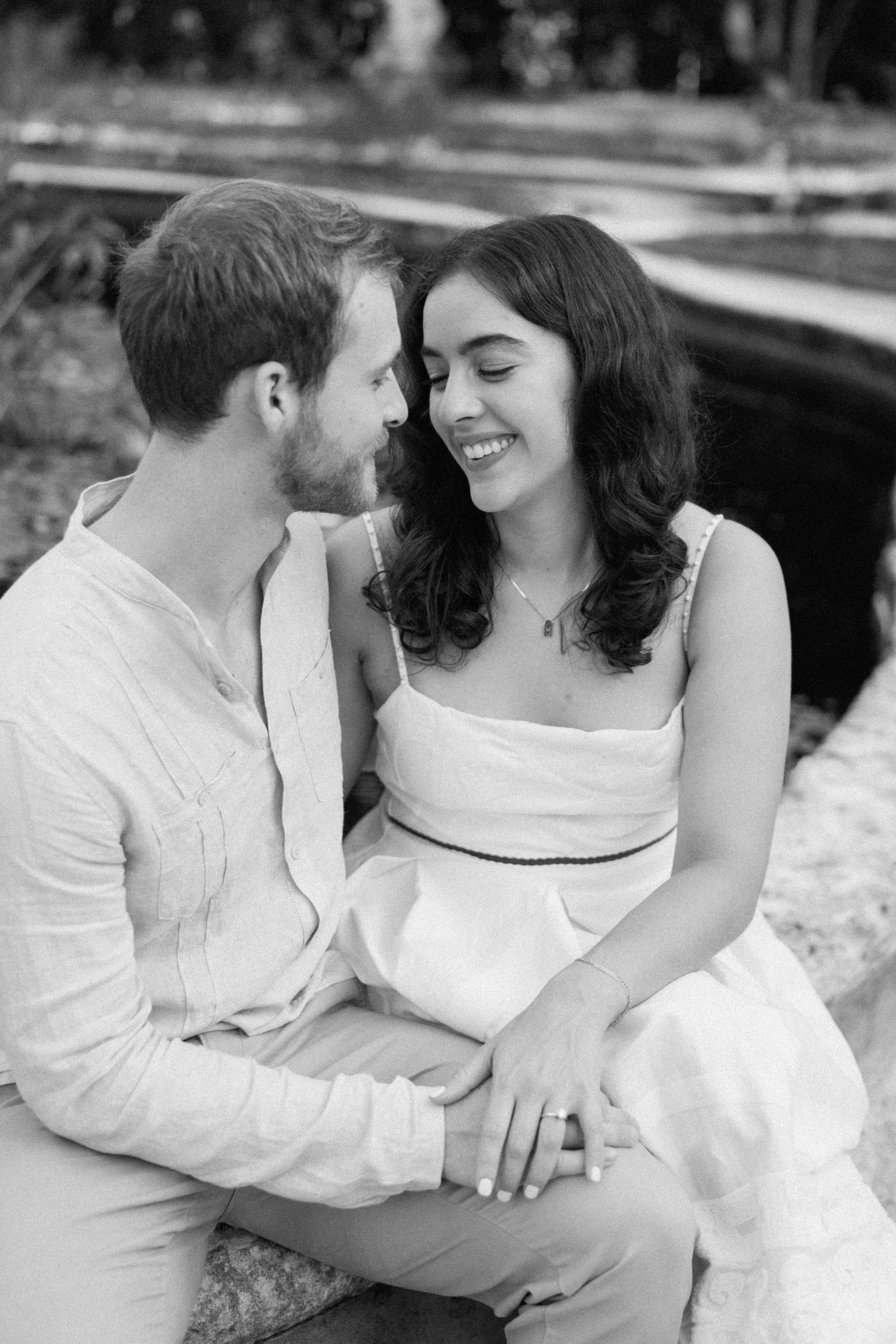 A romantic black and white portrait of a couple sharing an intimate moment outdoors.