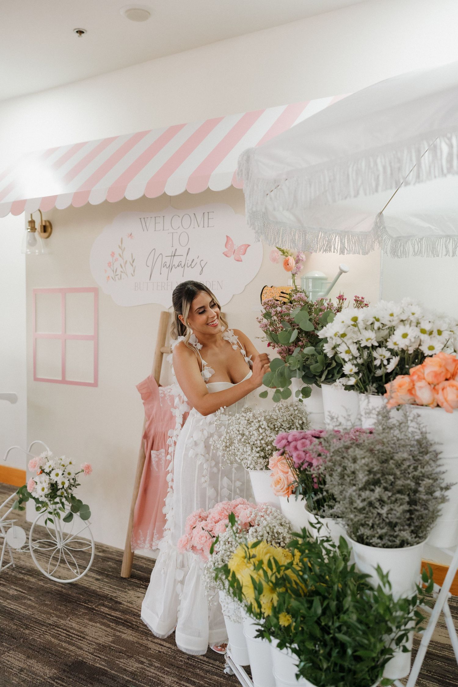 Pretty garden party setup with pink striped awning and floral arrangements.