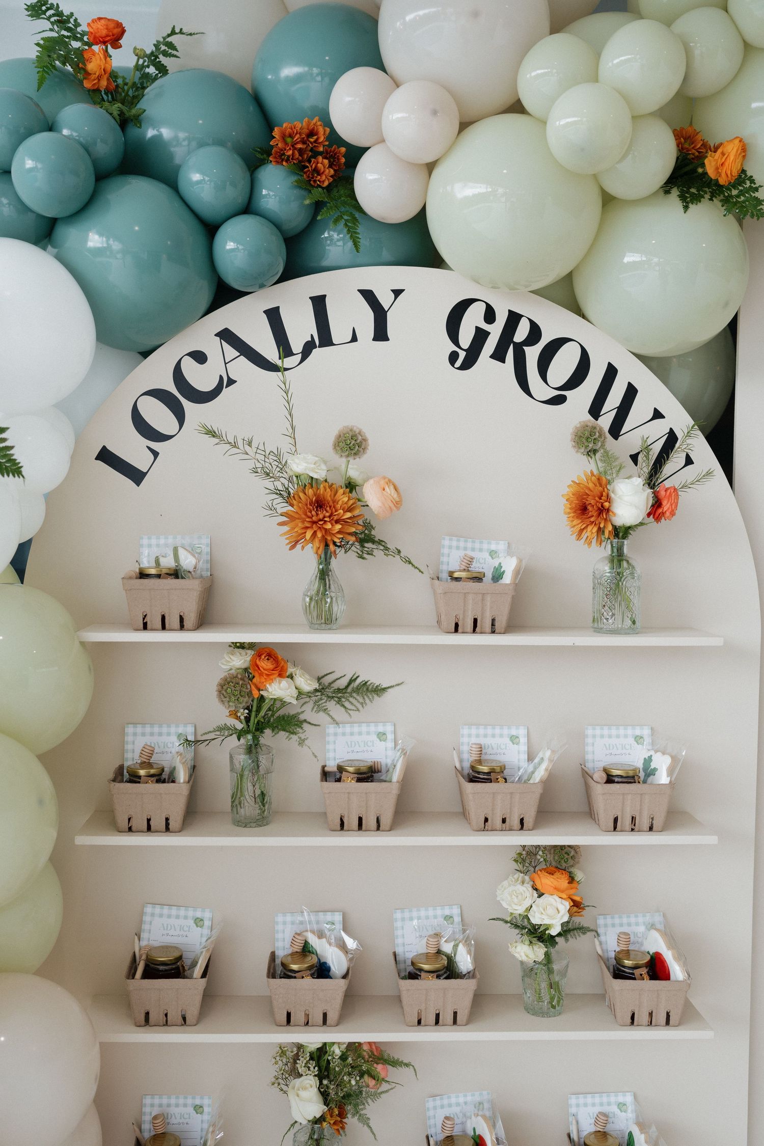 Event display with floating balloon arch and tiered shelving showcasing small retail products.