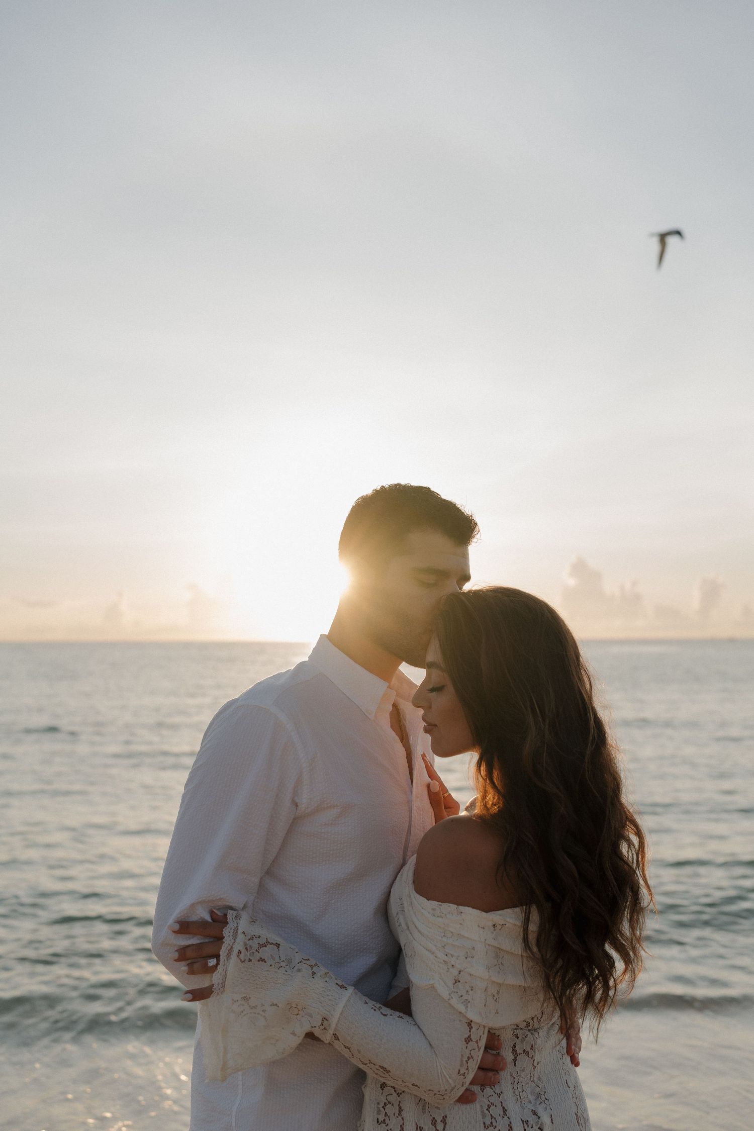 Sunset beach wedding portrait with golden light and ocean waves in background.