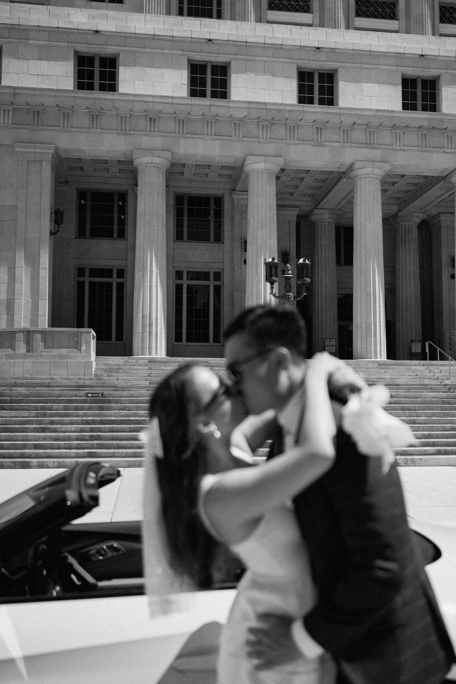 Black and white wedding portraits captured in front of a grand stone building with columns.