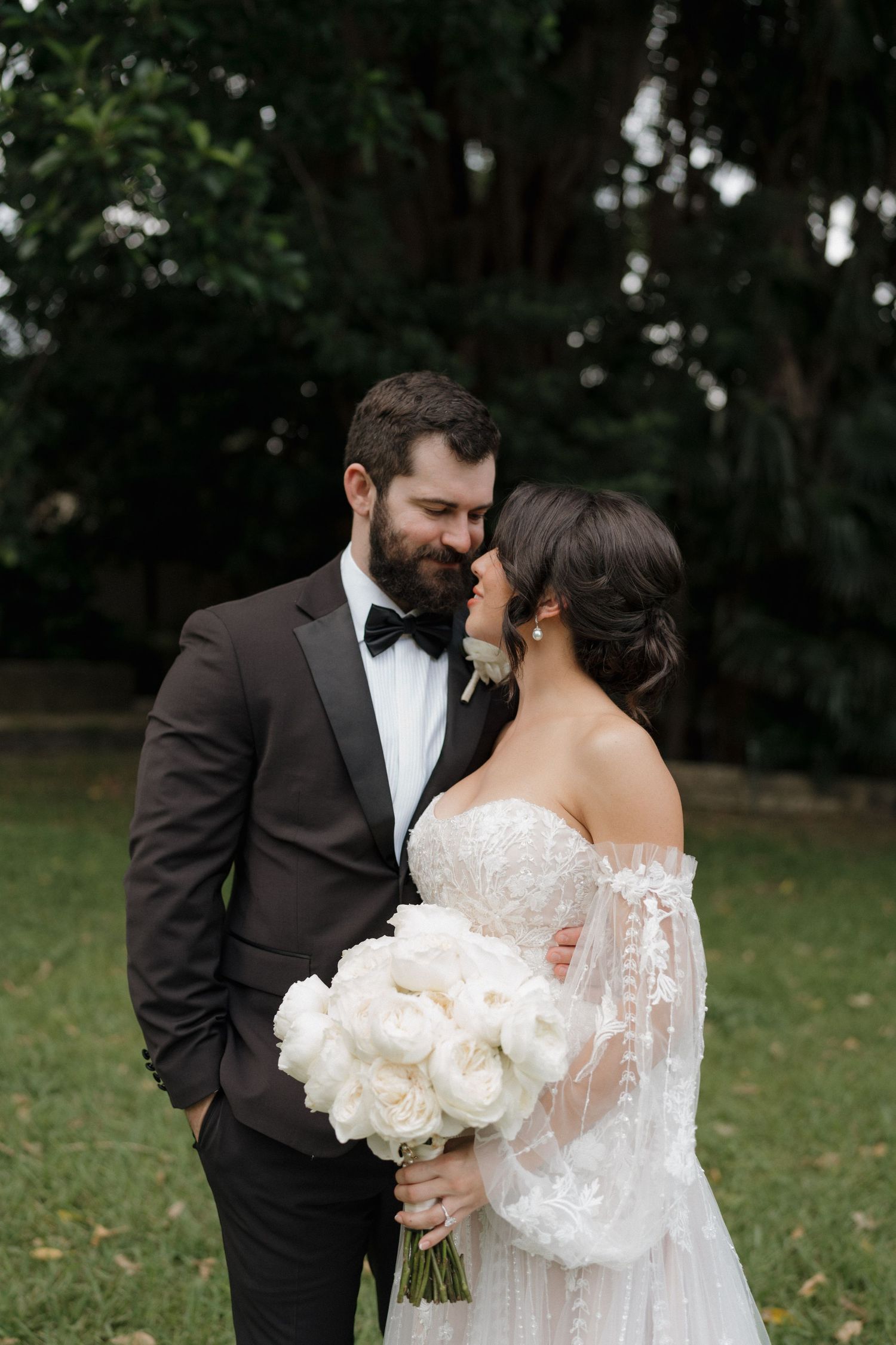 A couple embraces during their wedding photo session with a beautiful white bouquet.