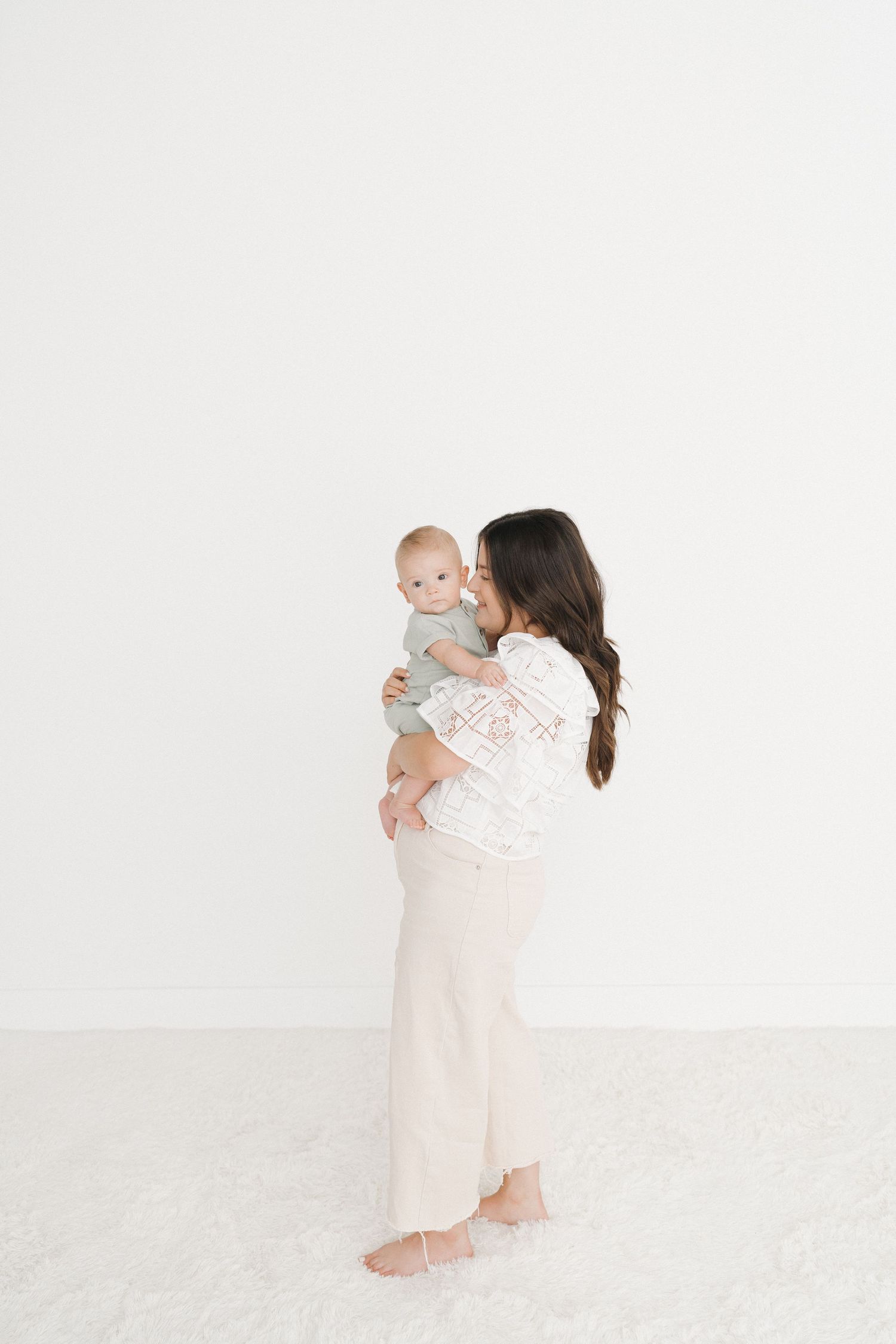 A tender moment between parent and baby against a minimalist white background.