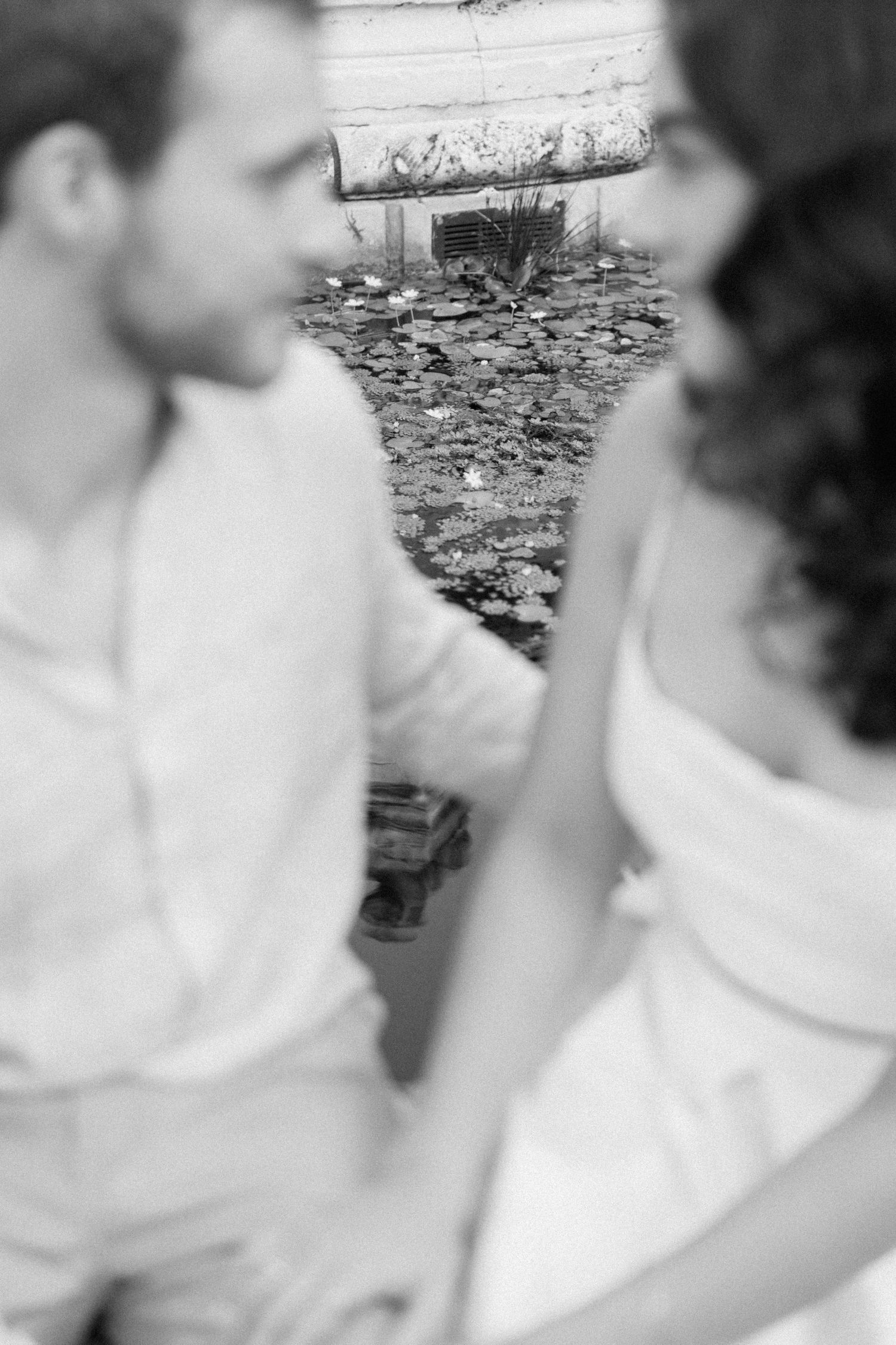 A black and white close-up shot of two people in an intimate moment outdoors.