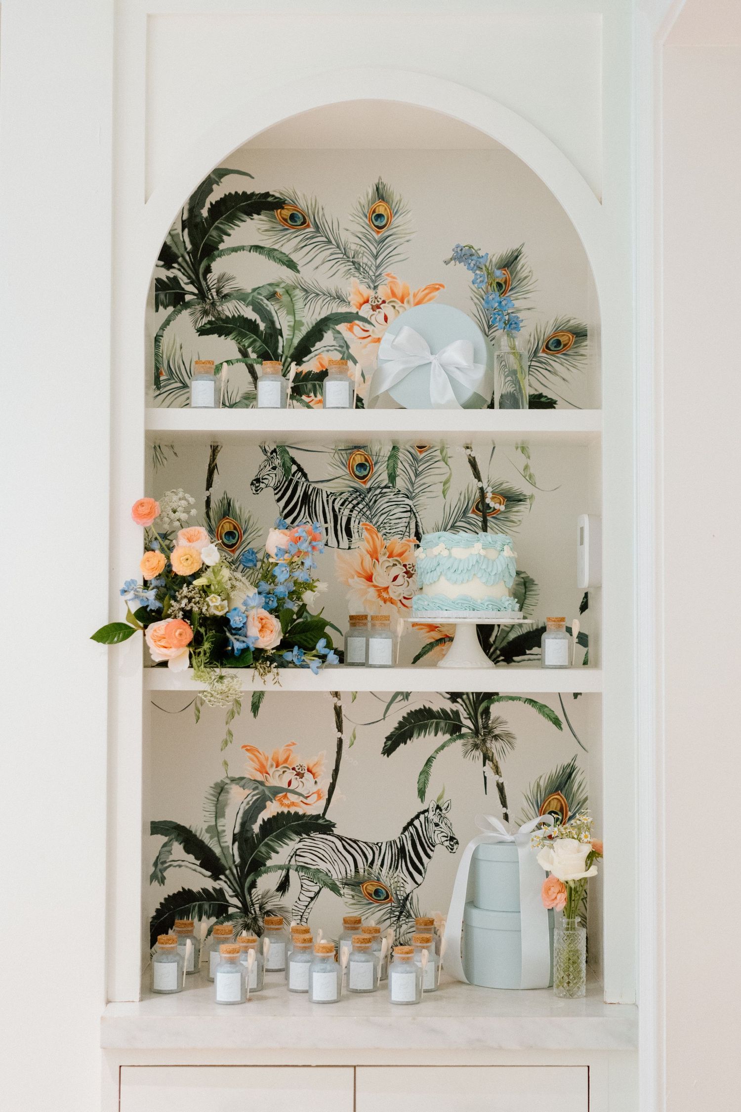 White built-in shelves decorated with tropical flowers and soft pastel decor elements.