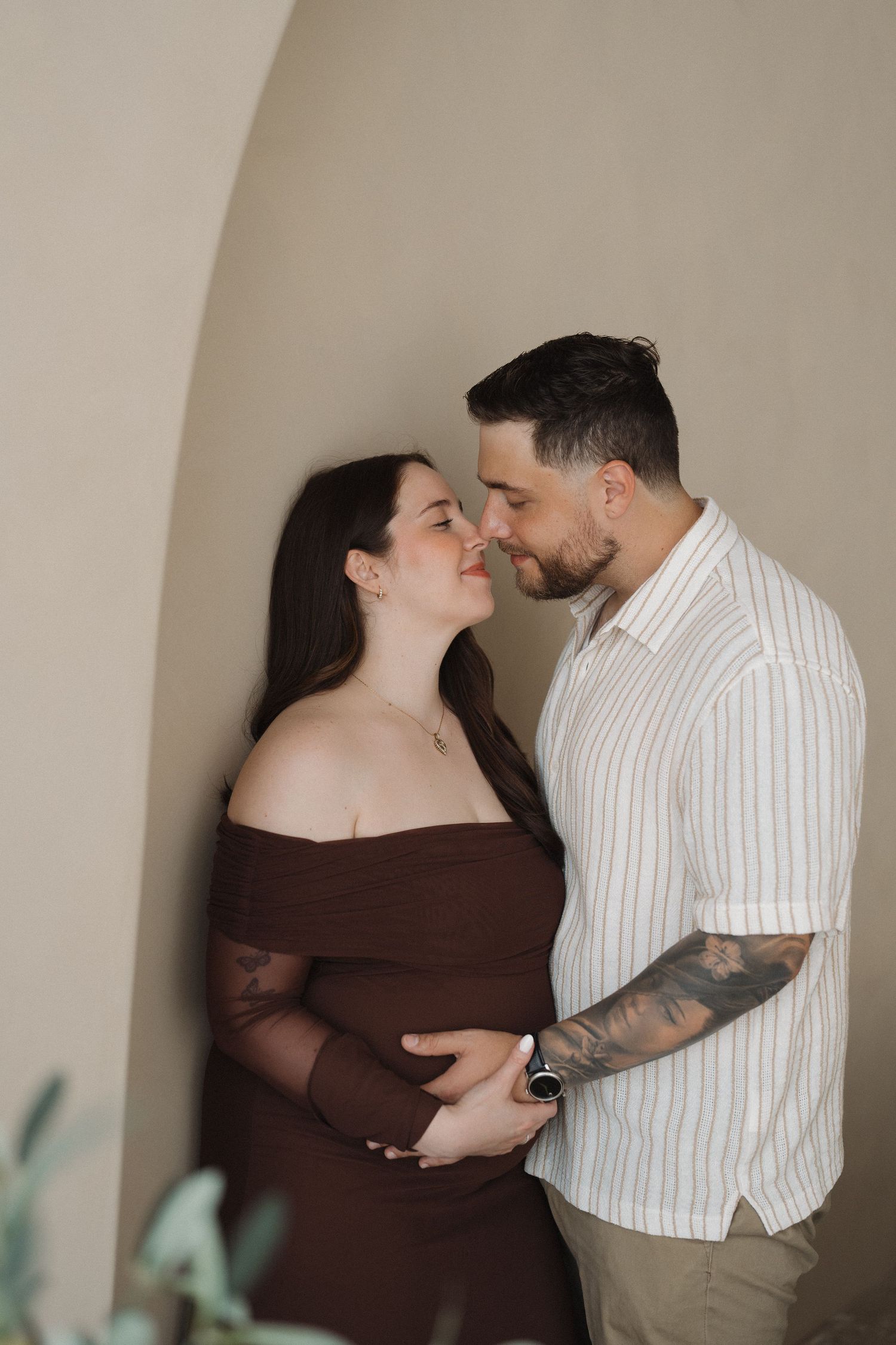Intimate maternity moment captured under an archway indoors.