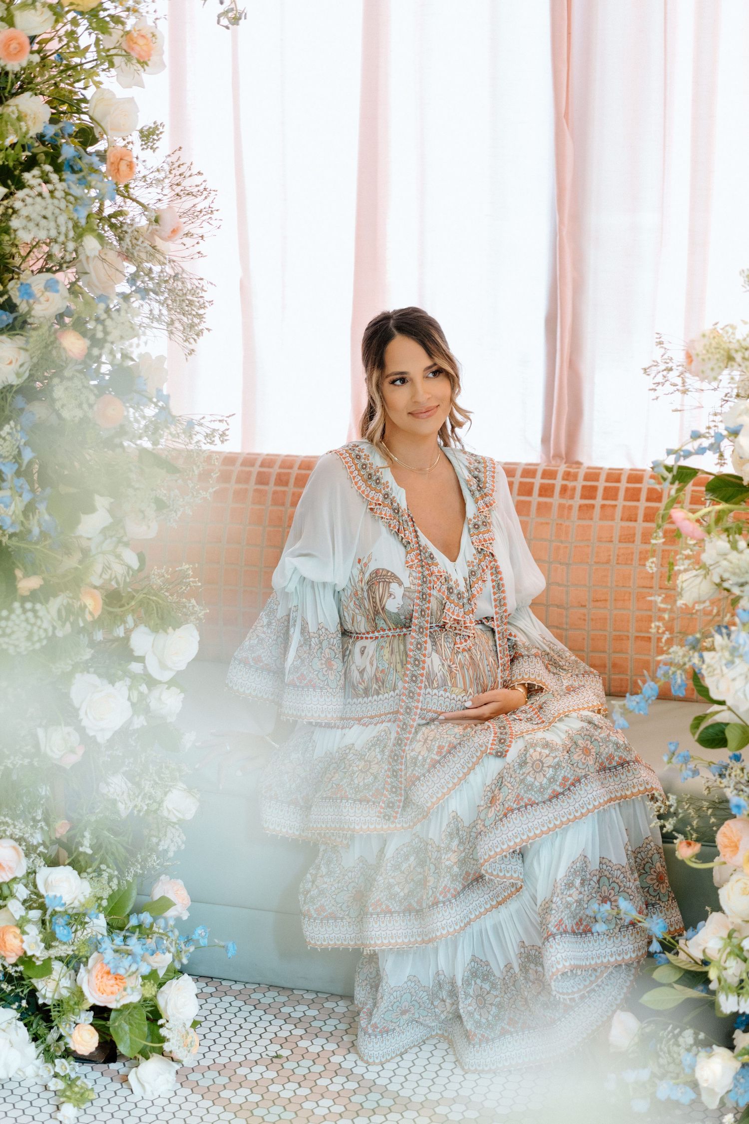 Ornate boho floral setup with someone seated on a wicker chair surrounded by delicate flowers.