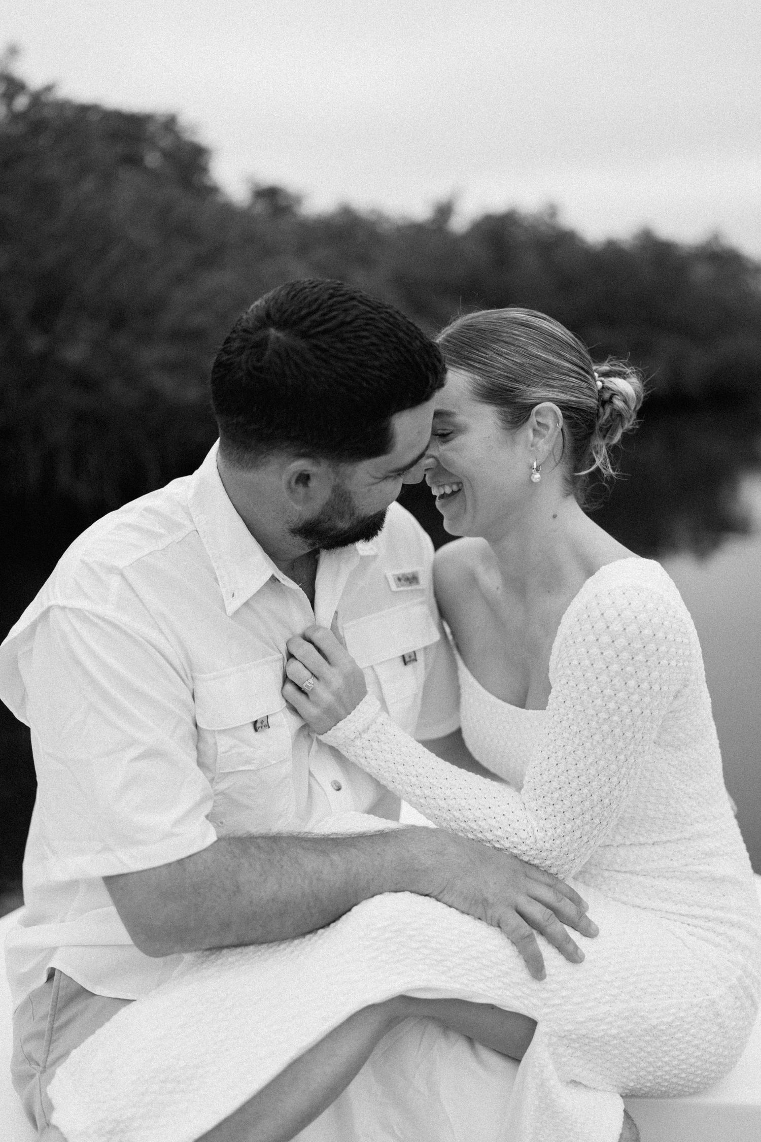 Romantic black and white photo series of couple embracing by water.