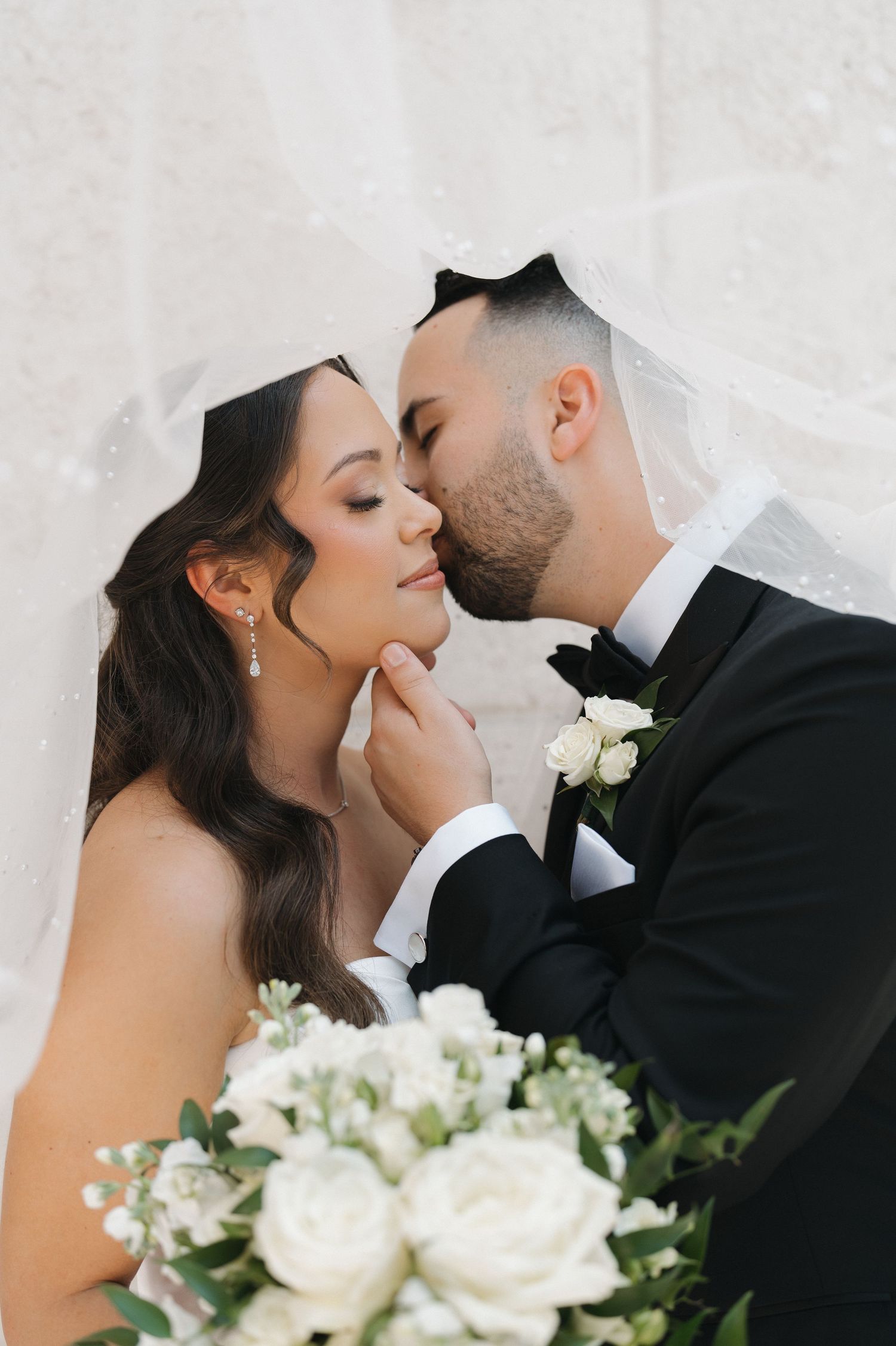 Tender wedding moment captured with white roses and delicate veil.