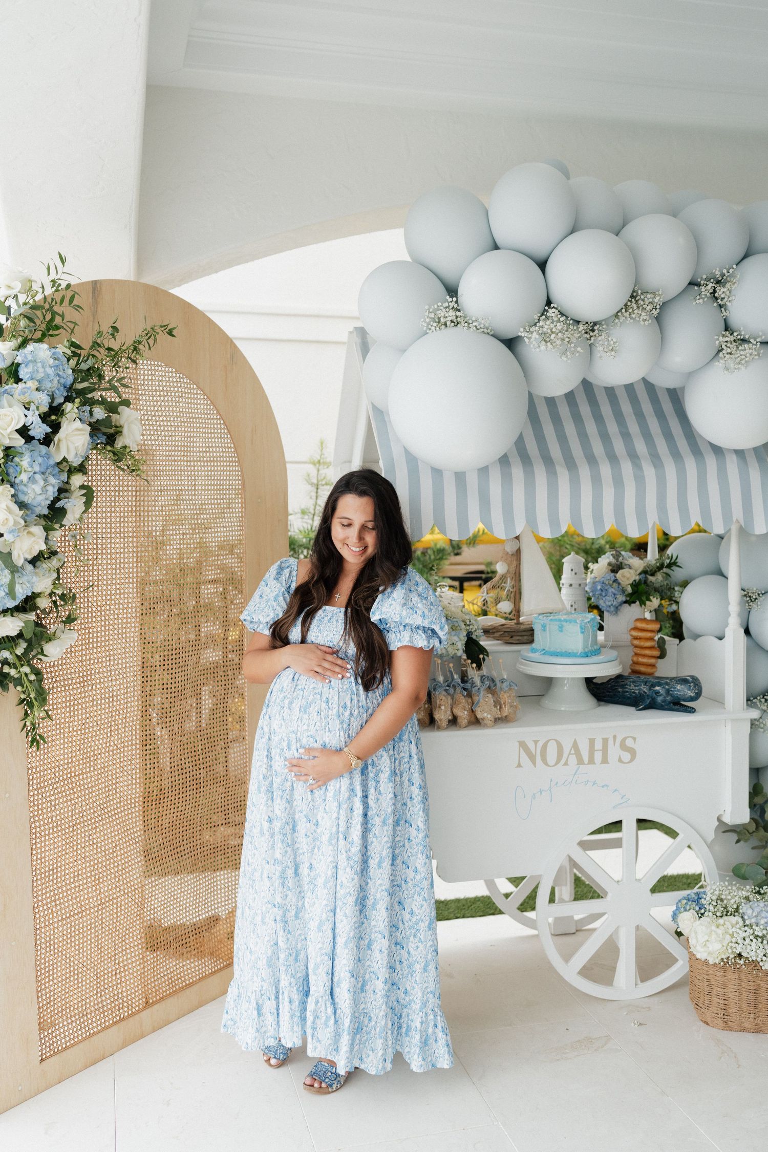 Party space with blue balloon garland, wooden cart and rustic arched backdrop details.