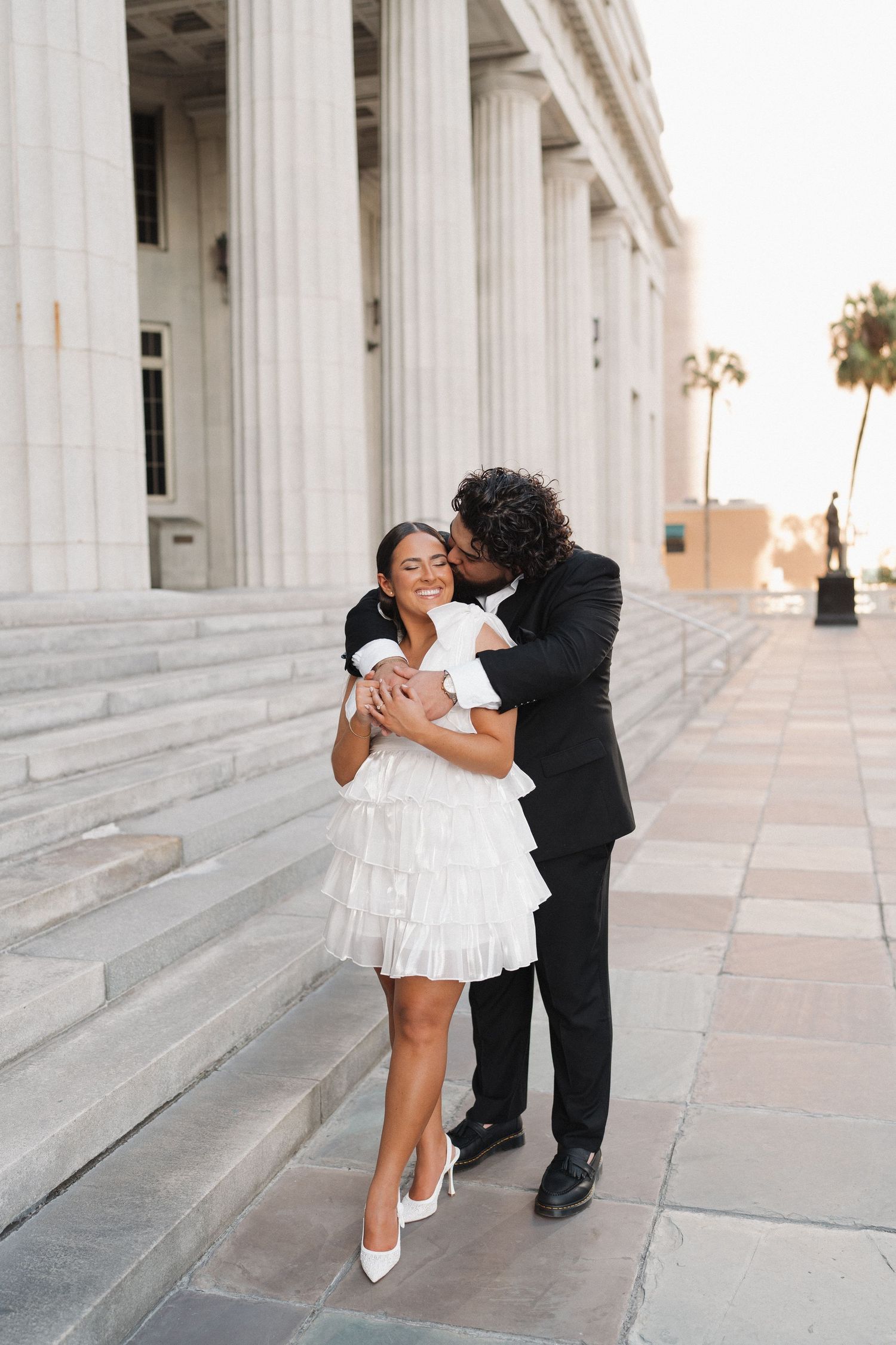 A joyful embrace captured in front of classical white pillars at golden hour.