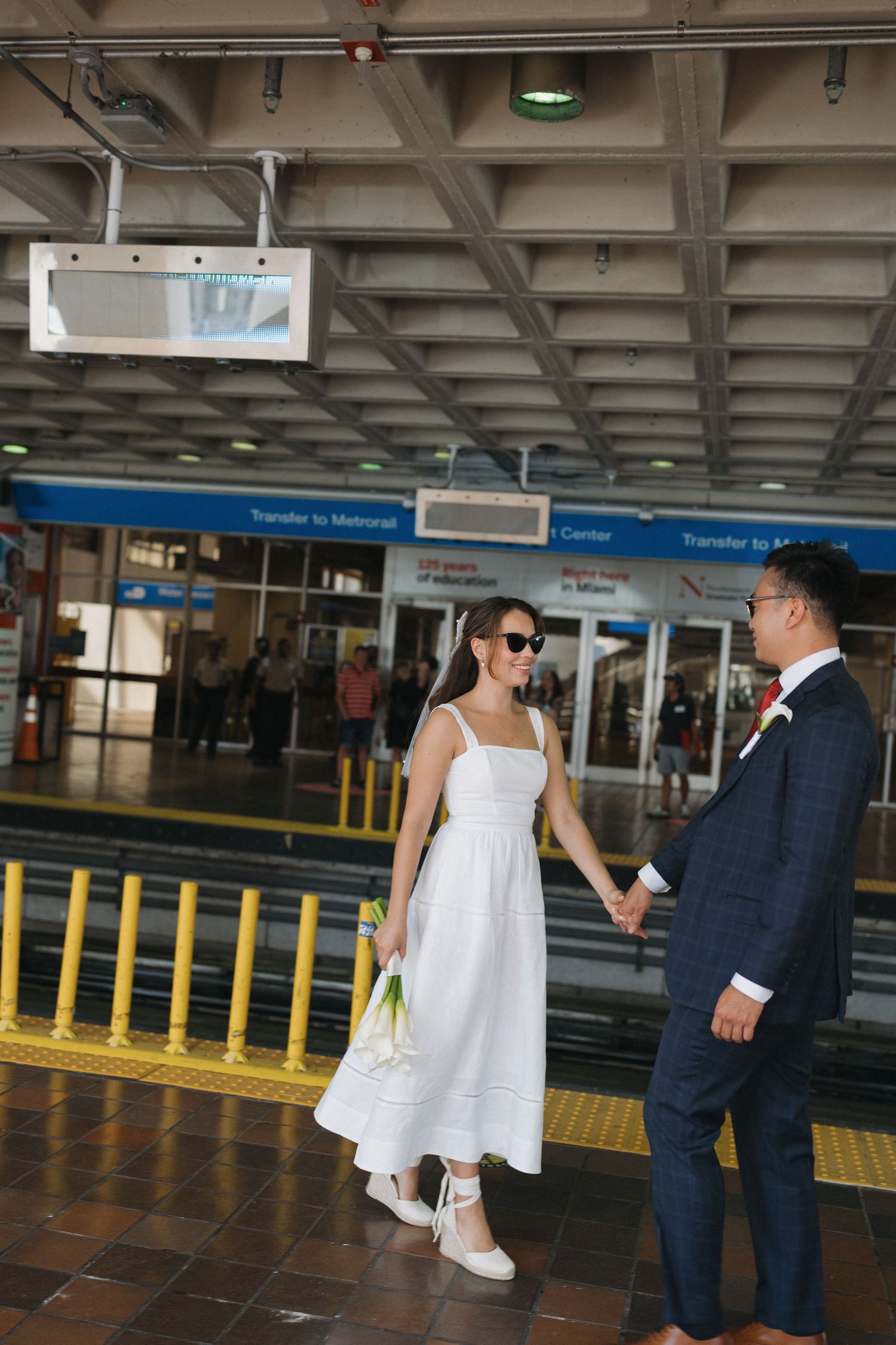 Newlyweds exploring urban transit station in formal wedding attire.