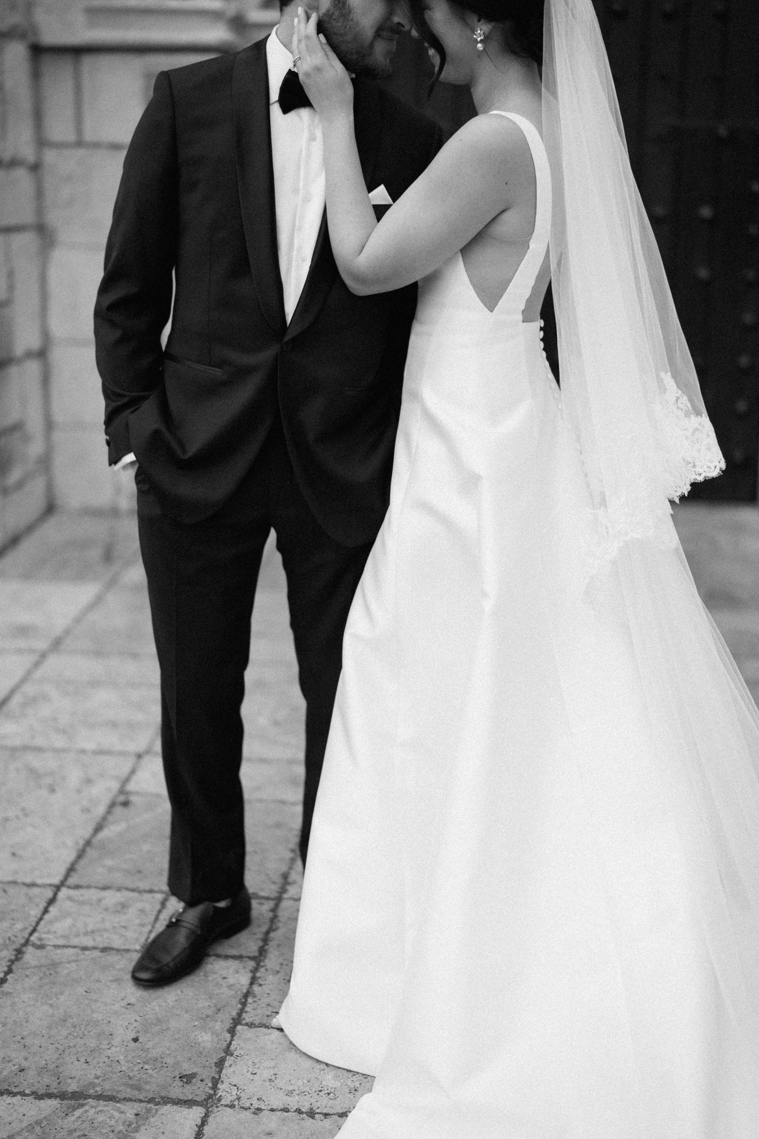 Black and white romantic wedding portrait showing details of dress and tuxedo.