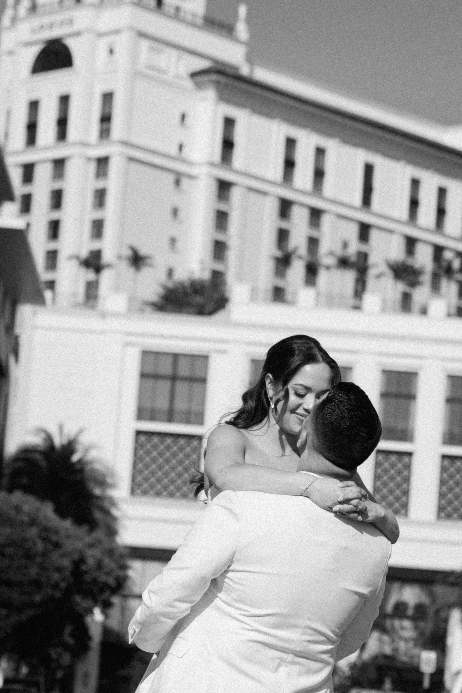 Intimate black and white moment between newlyweds outside historic building.