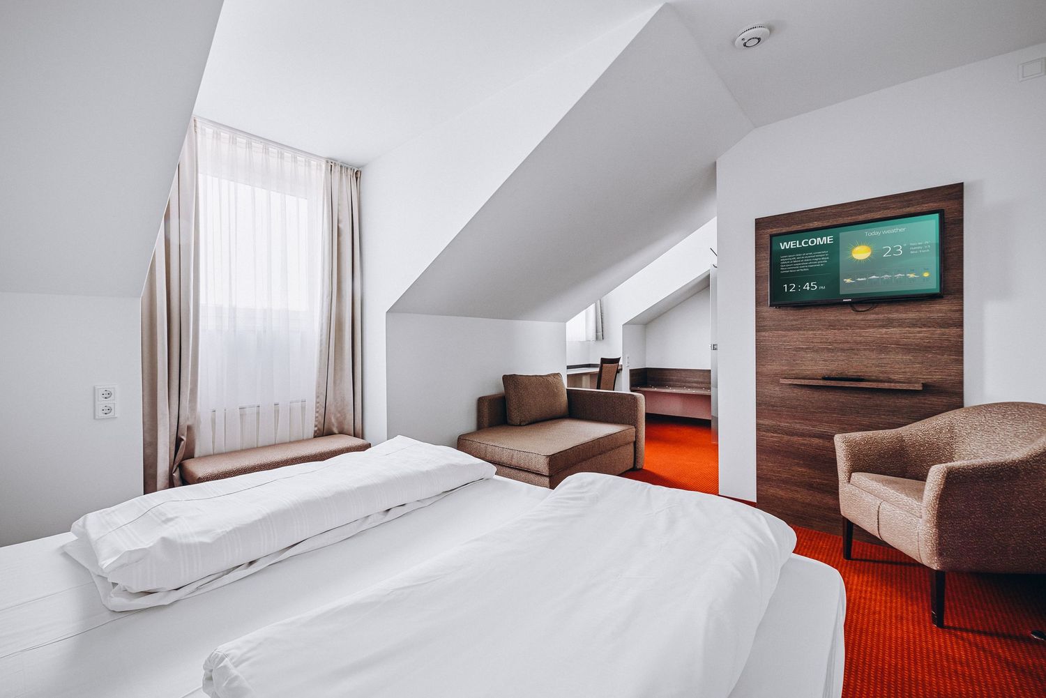 Modern bedroom with warm wood paneling and bright red carpet featuring a minimalist bed frame and white curtains.