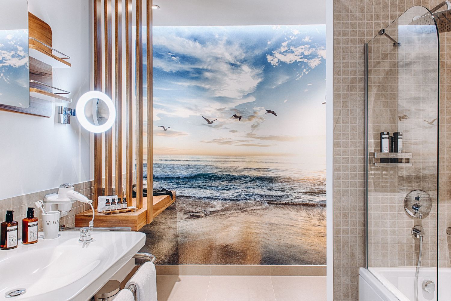 Modern bathroom interior features wooden slats, neutral tones, and coastal artwork in a luxurious spa-like setting.