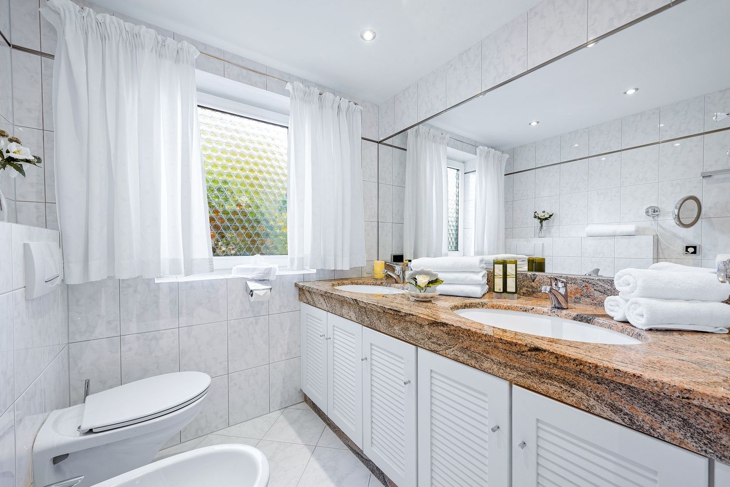 A stylish white bathroom interior featuring grey marble countertops, modern fixtures, and natural wood accents.