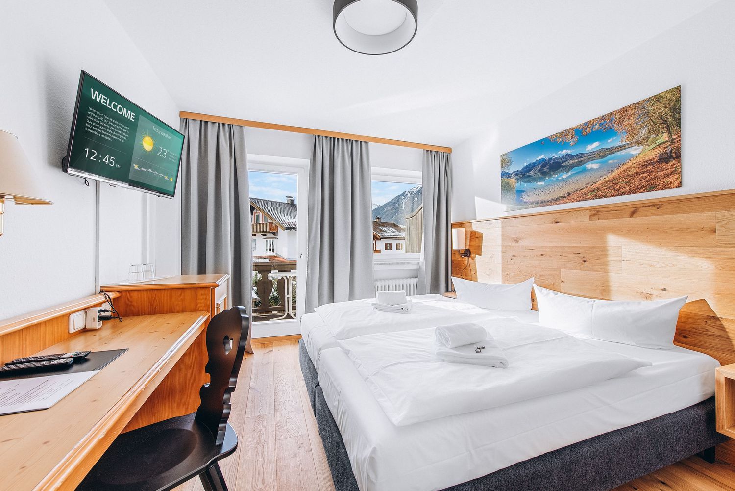 Modern hotel room interior with wooden furniture, gray curtains, wall-mounted TV, and a cozy double bed.