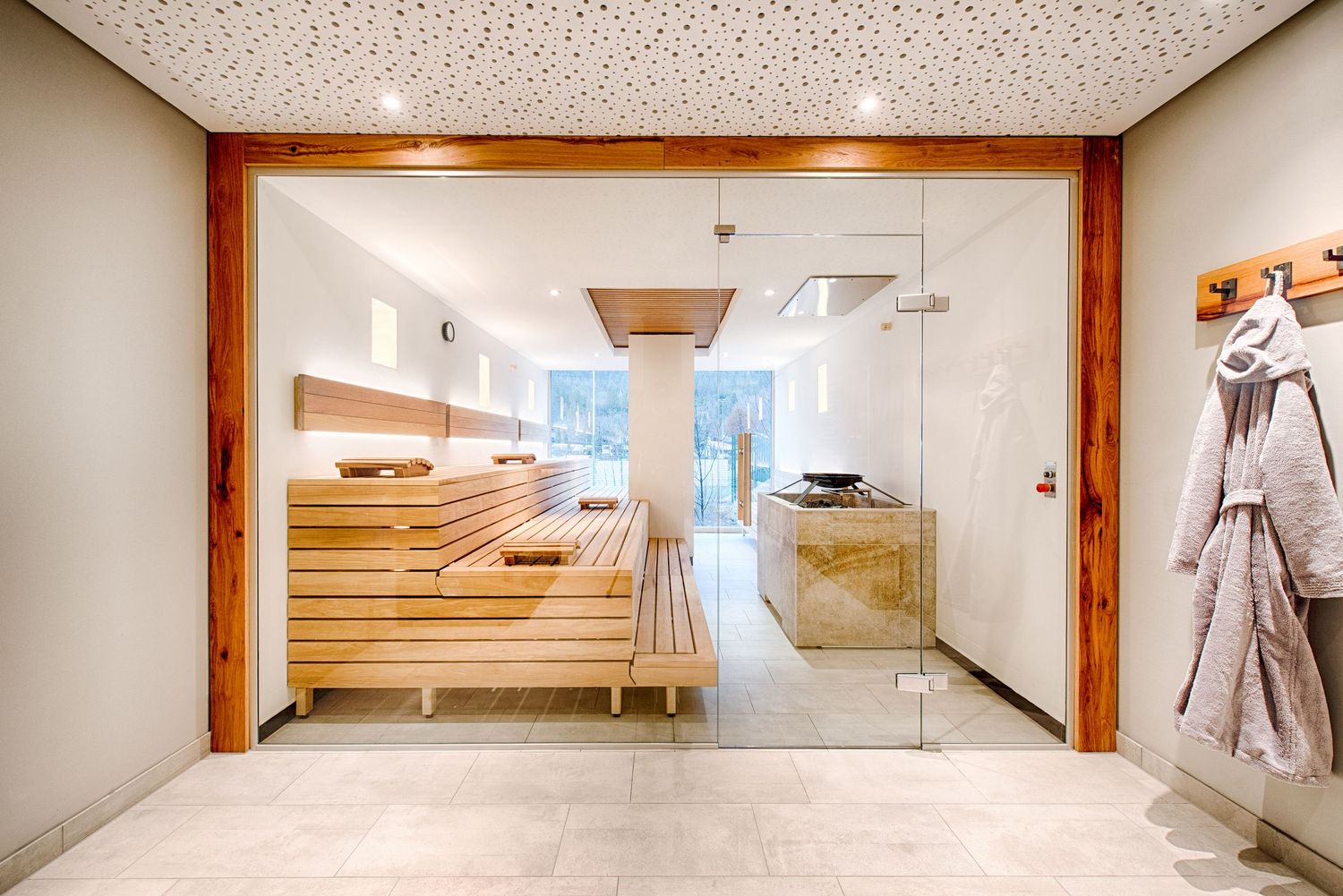Modern spa entrance with glass doors, wooden sauna benches, and clean minimalist design.