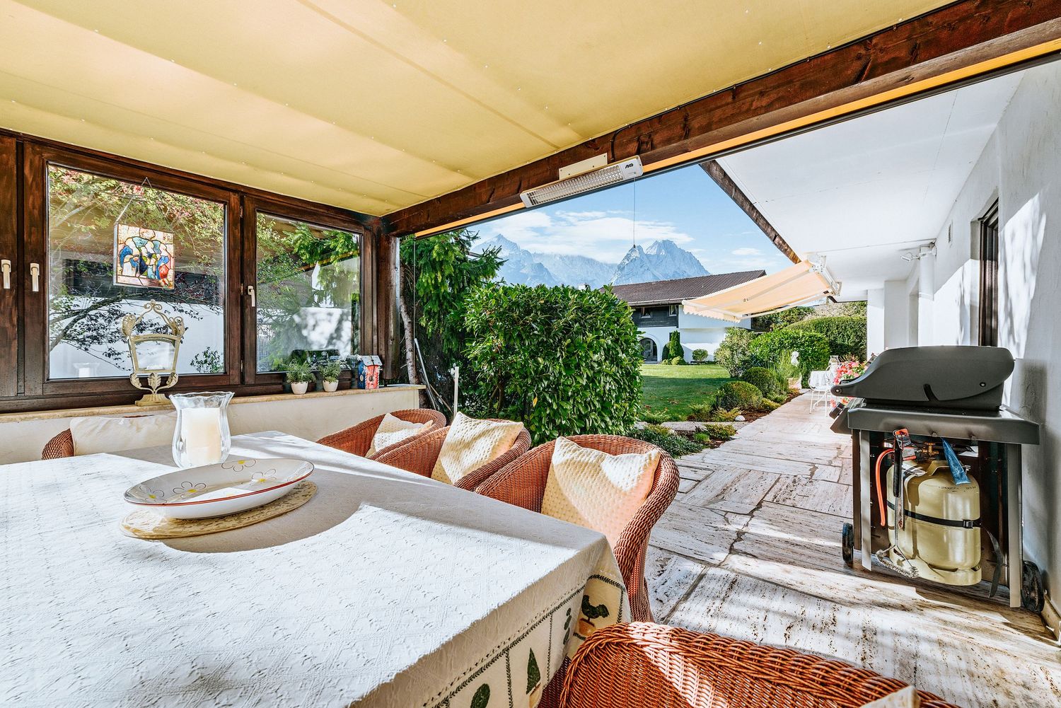 Cozy covered patio dining area with mountain and lake views featuring a rustic wood table and cast iron stove.