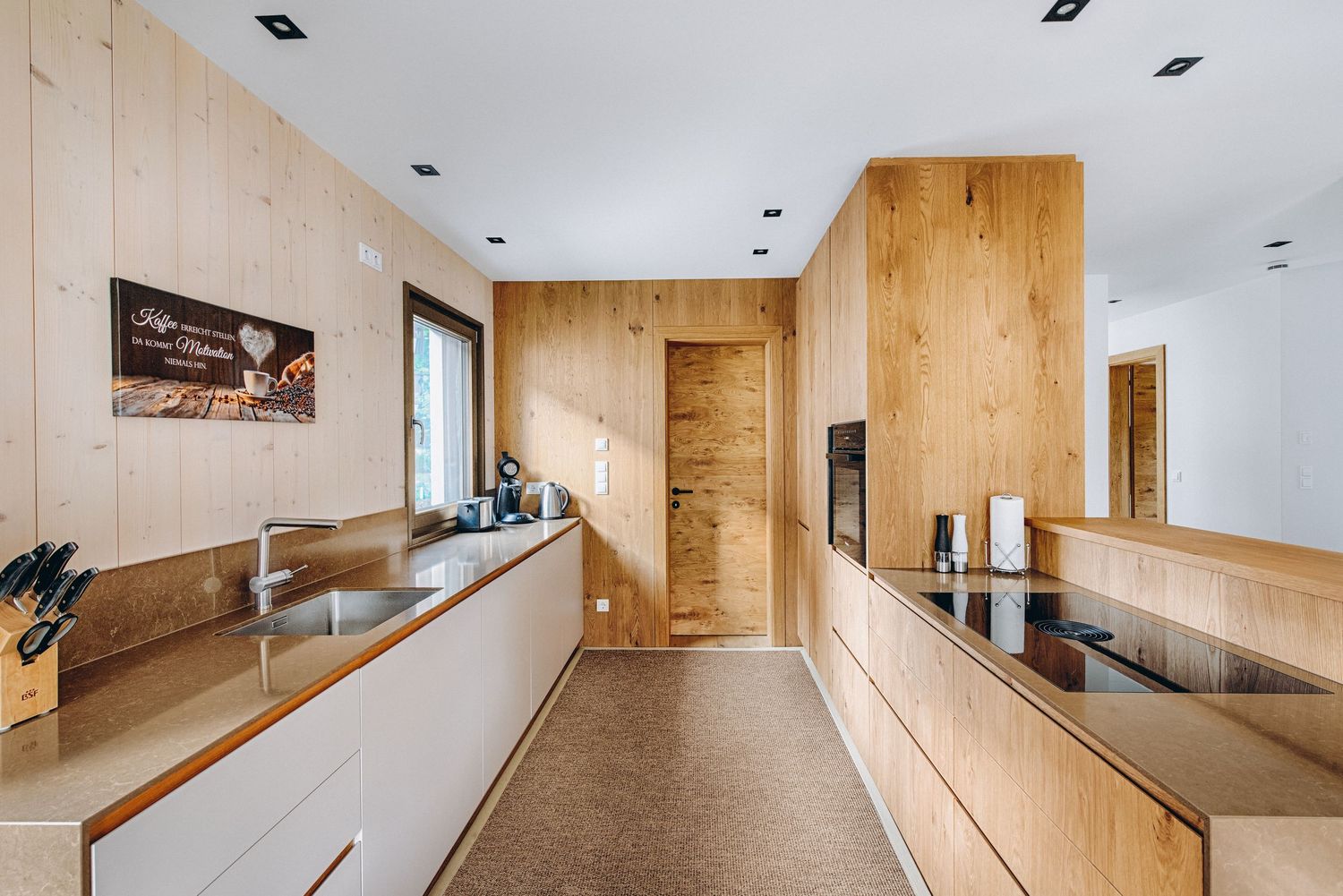 Modern kitchen interior with wooden cabinetry and sleek minimalist design featuring built-in appliances and clean lines.