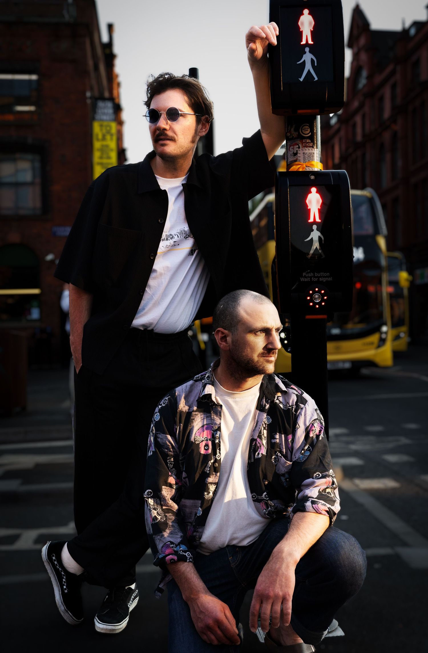 The French duo TRM BSR leaning on a traffic signal in Manchester, UK.