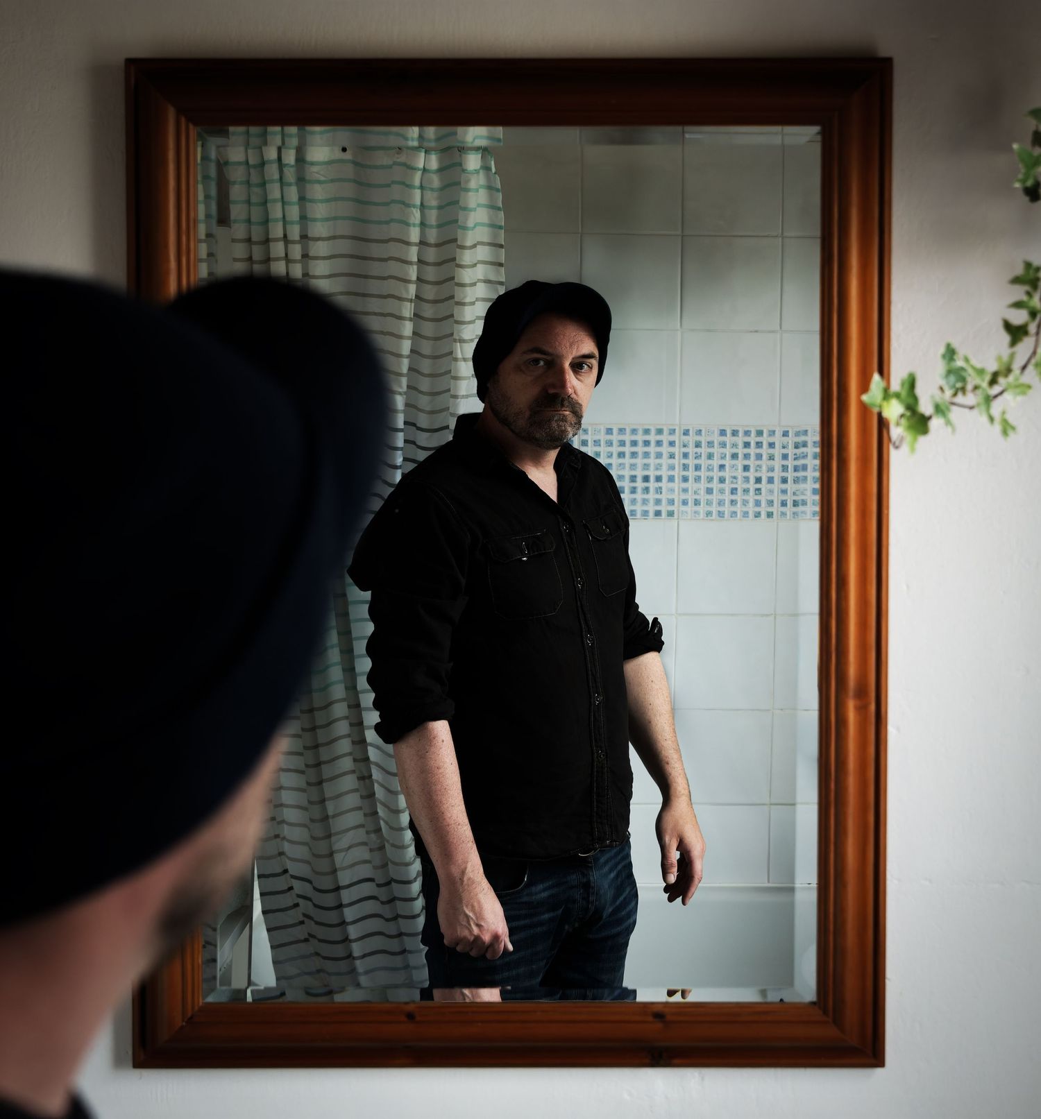 'Portrait of a Self-Portrait'. A man looking in a bathroom mirror; we see his reflection, but no camera.