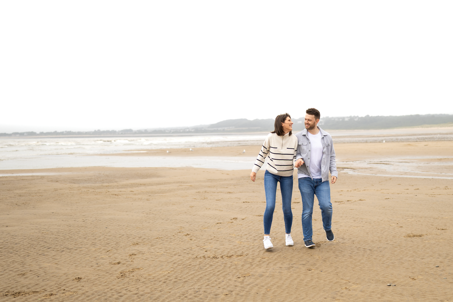 Couple enjoying a romantic walk along an empty beach at sunset.