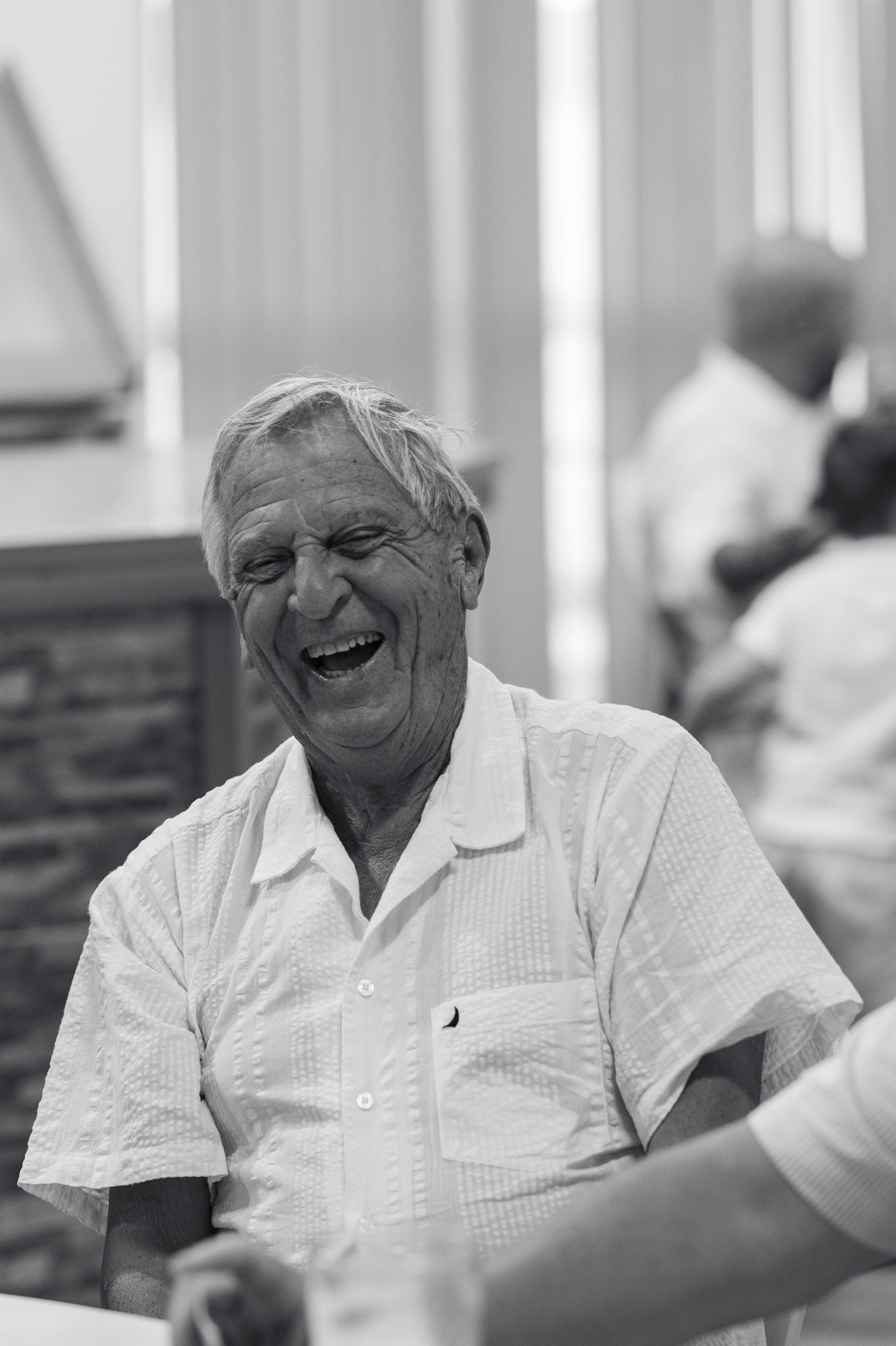 Candid black and white portrait of wedding guest showing joyful laughter.