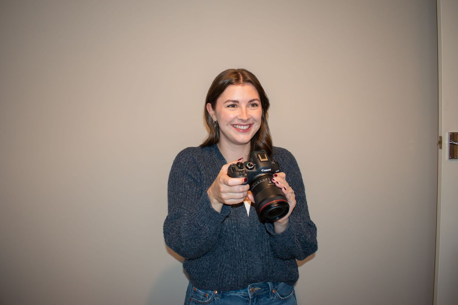 Woman in blue sweater holding a camera and taking photographs.