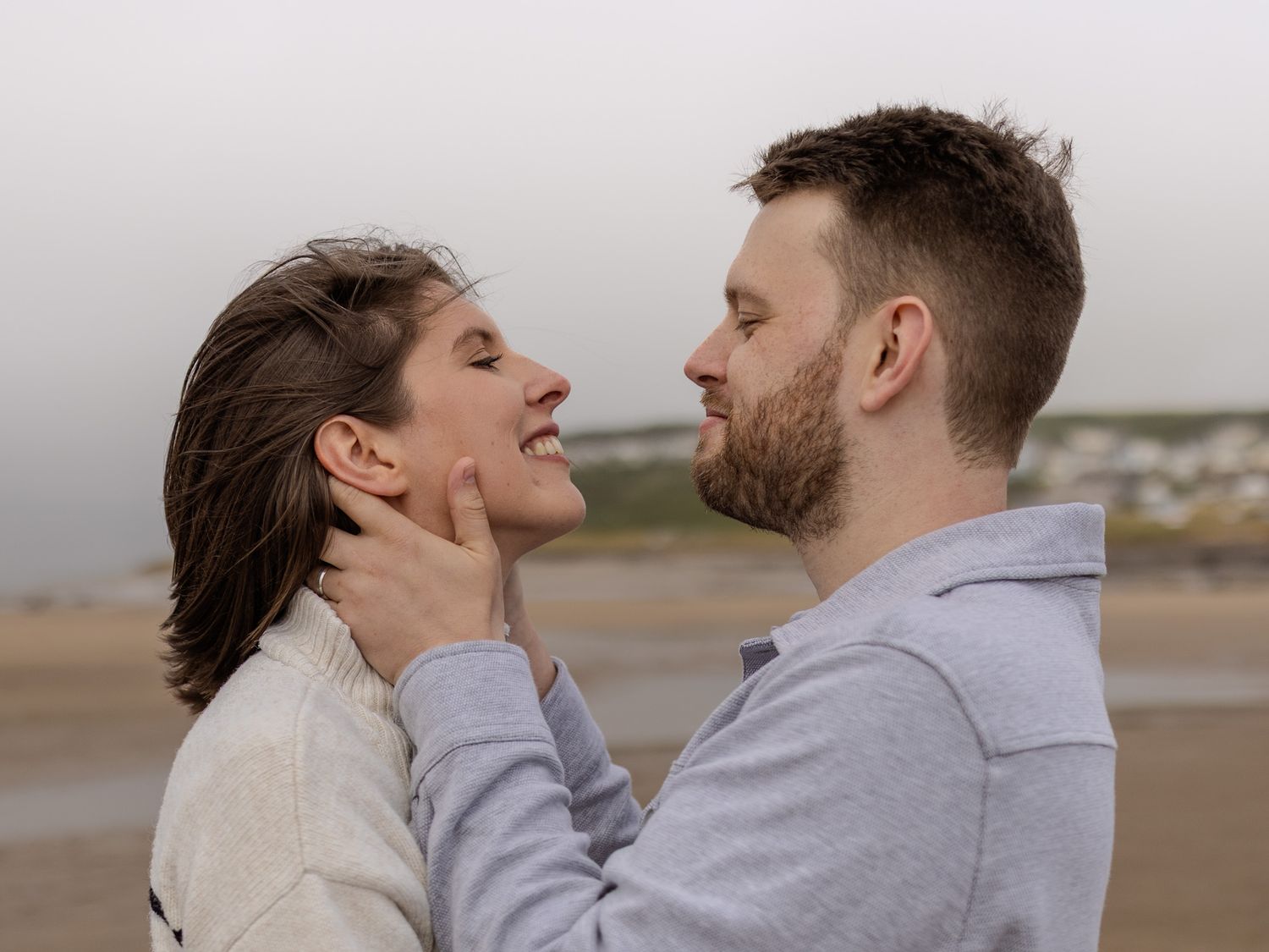 Intimate couple moment captured during a cloudy beach photoshoot.