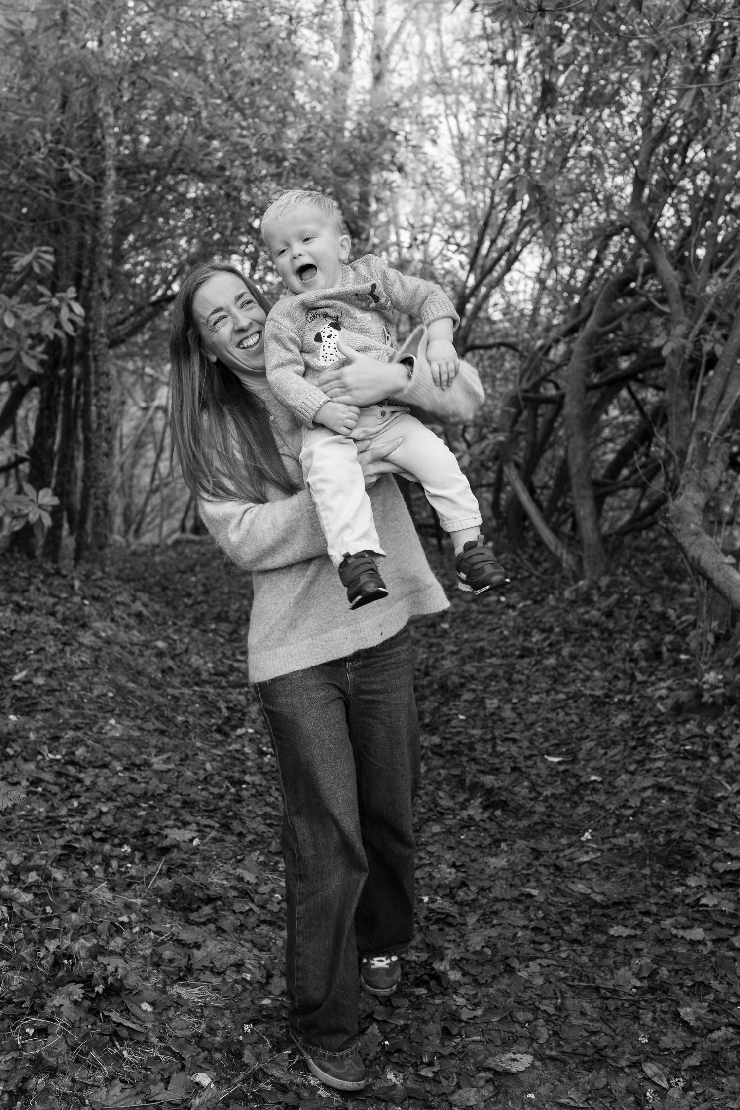 A series of black and white photos capturing playful moments in a wooded area.