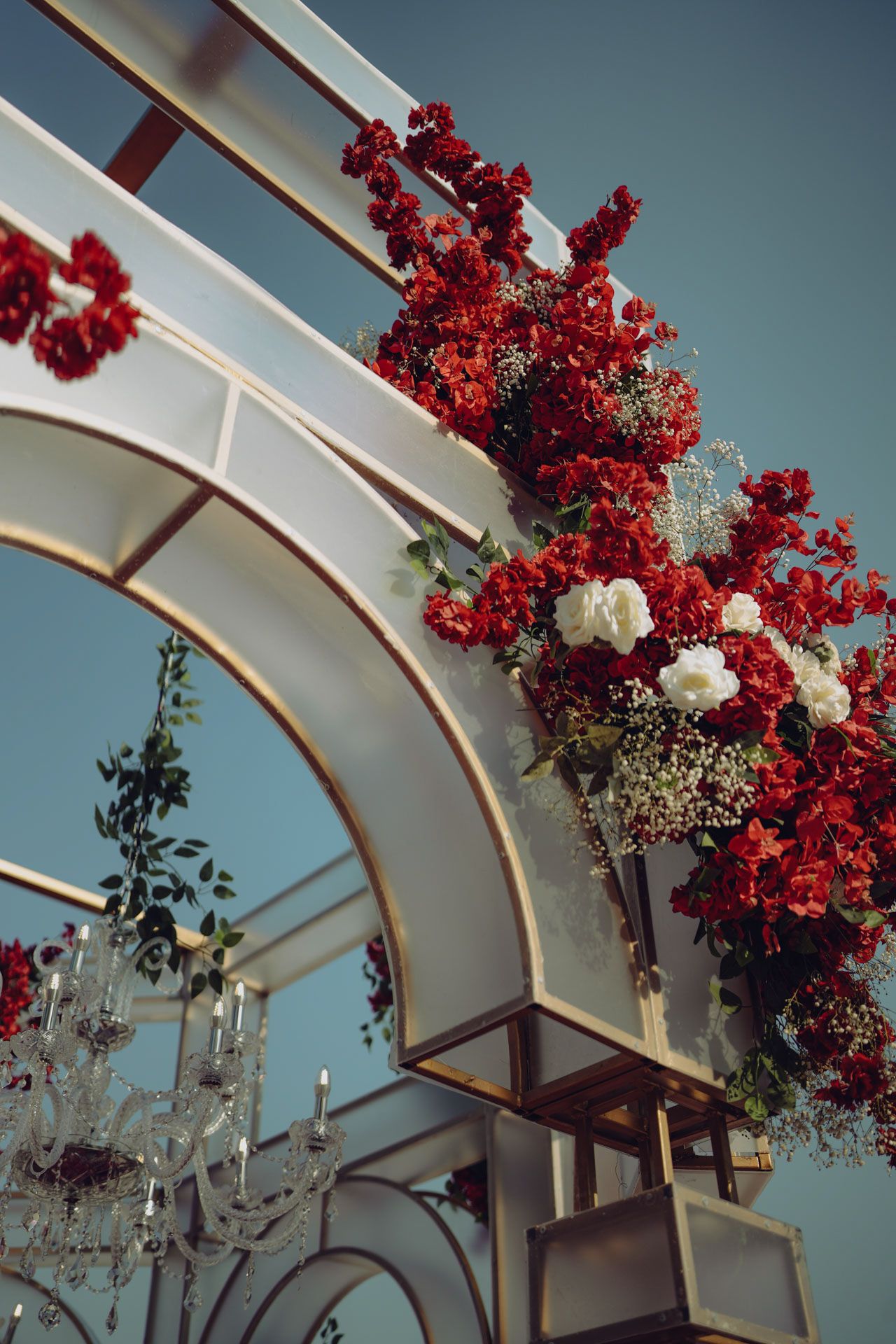 red and white floral mandap under open sky designed to elevate the ambiance of a high-end multicultural wedding celebration.