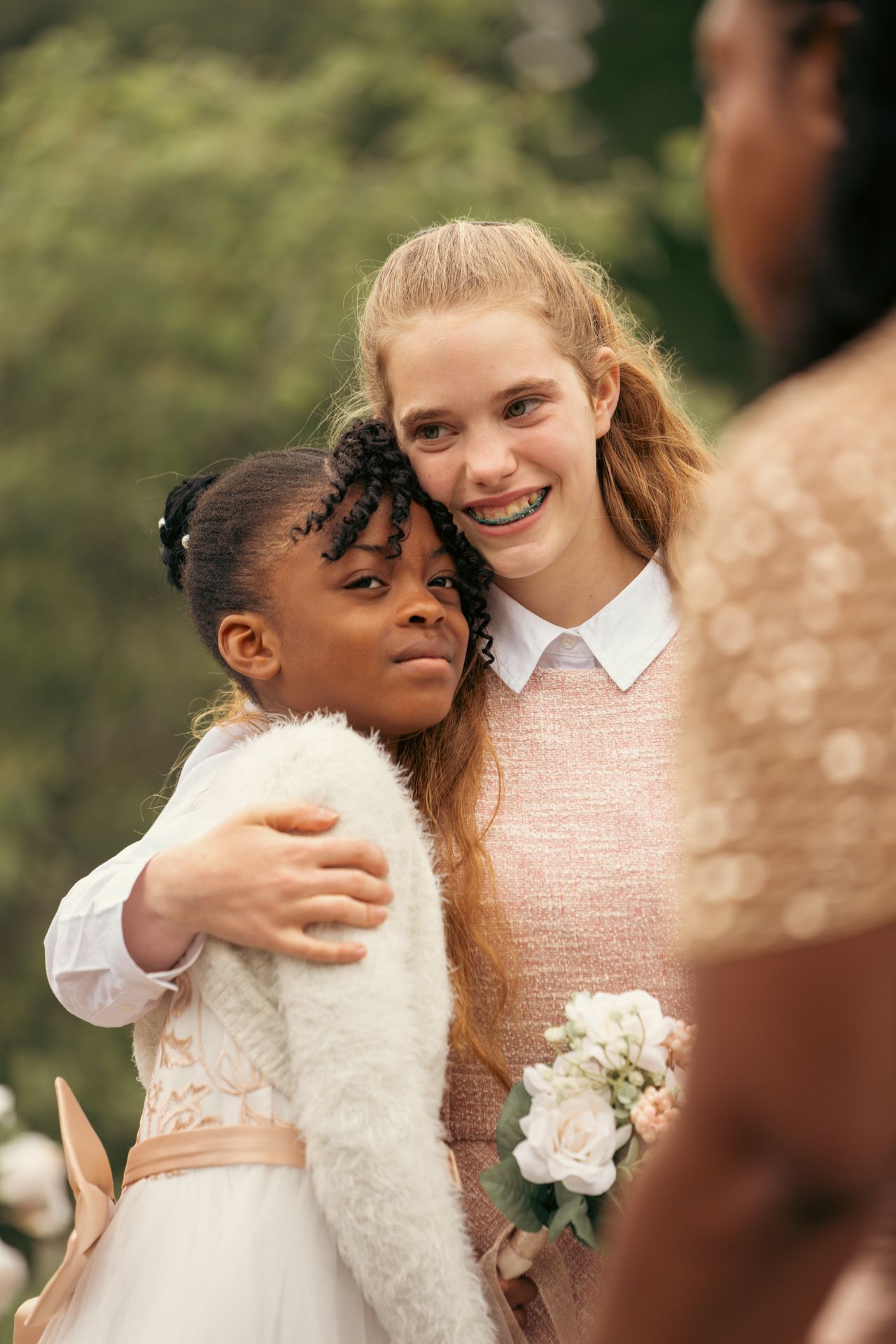 Heartfelt moment captured: cousins hugging together for family shoot session at a white wedding