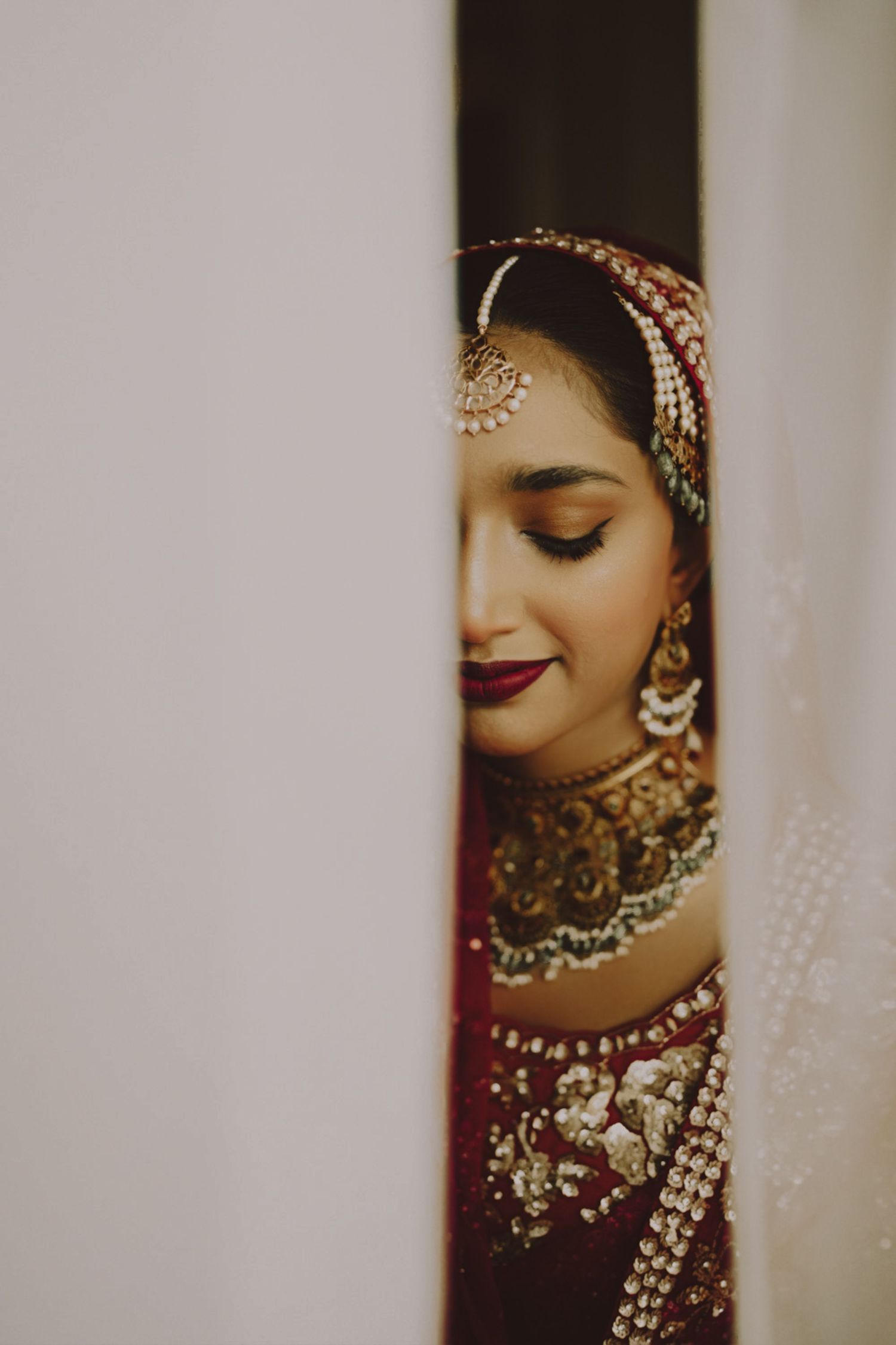 South Asian engagement photo showing the bride’s intricate jewelry and glowing smile as she holds her fiancé’s hand.