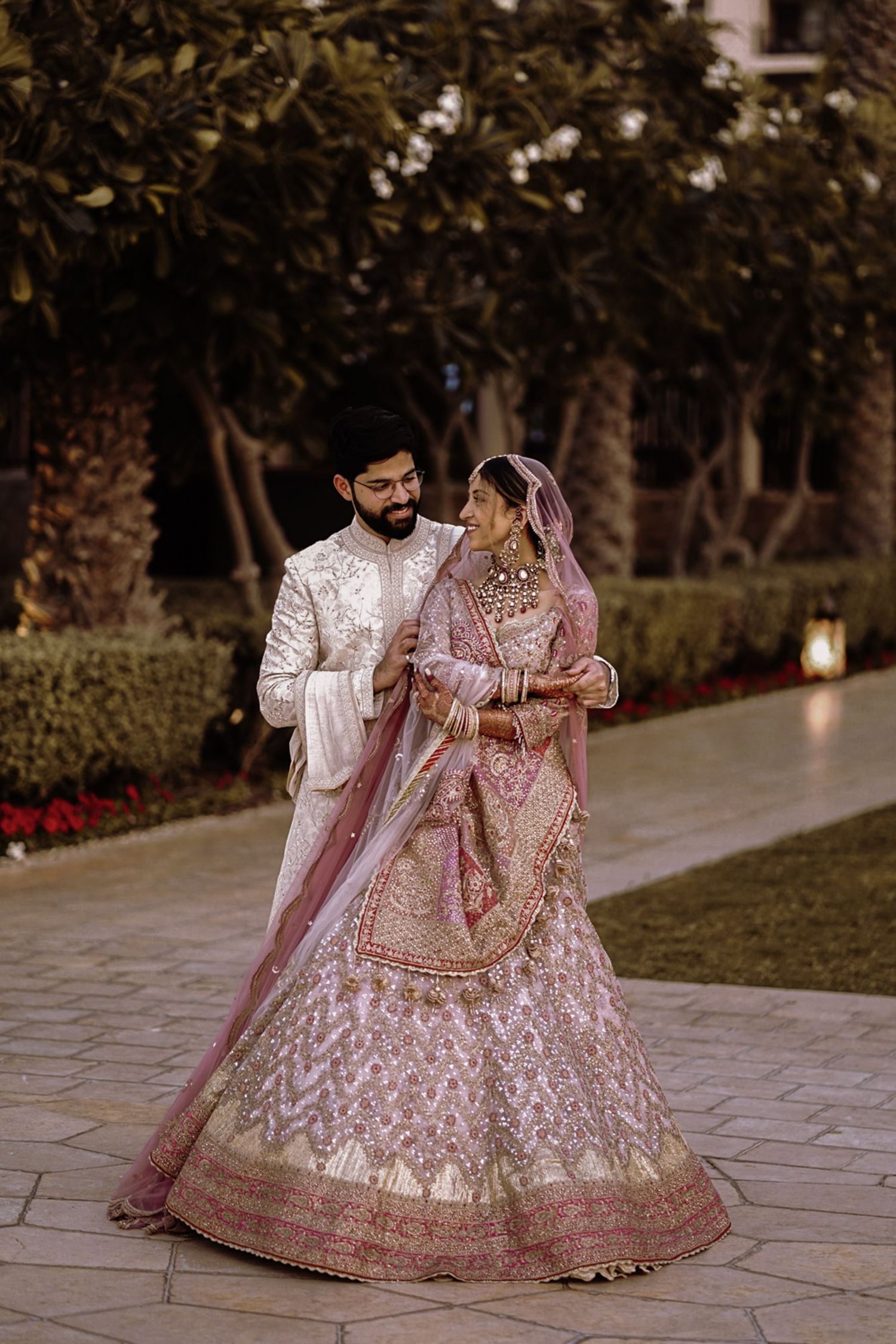 Bride-to-be in traditional red lehenga with golden embroidery posing for a regal engagement portrait.