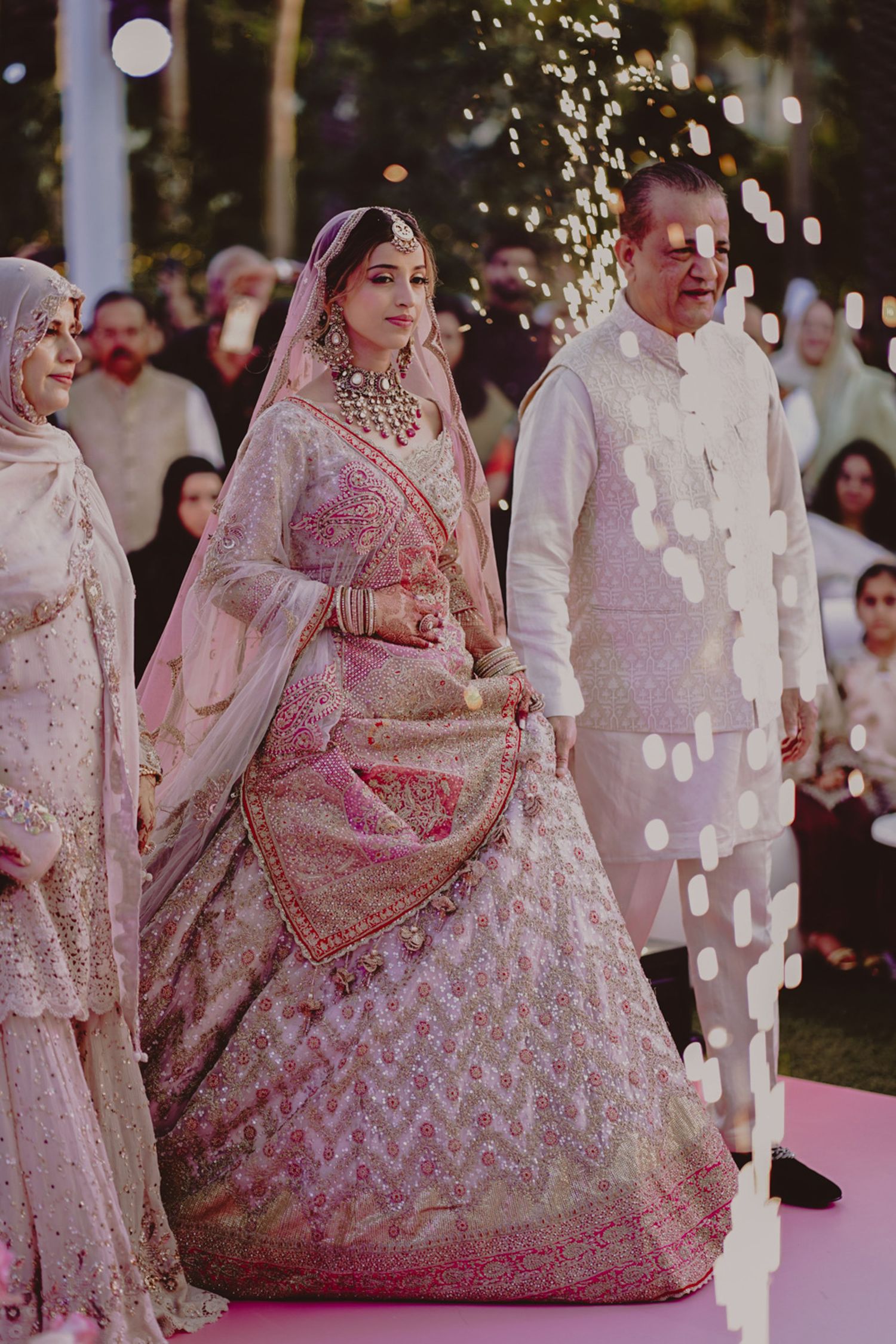 Engagement photo of bride twirling in pastel pink lehenga with delicate gota work.