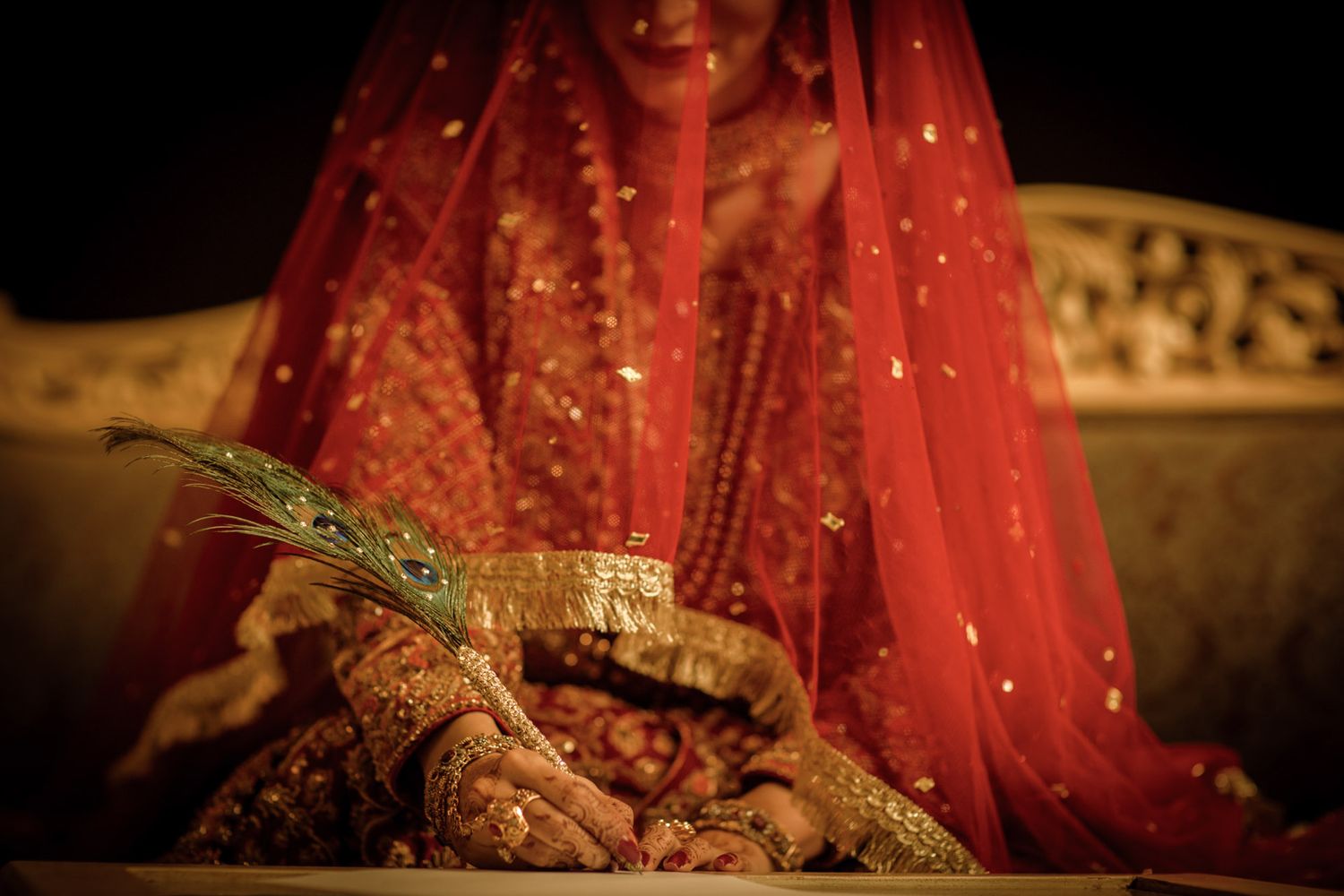 Nikkah ceremony in Lahore with the bride in red lehenga and groom in sherwani, framed by rich floral decor.