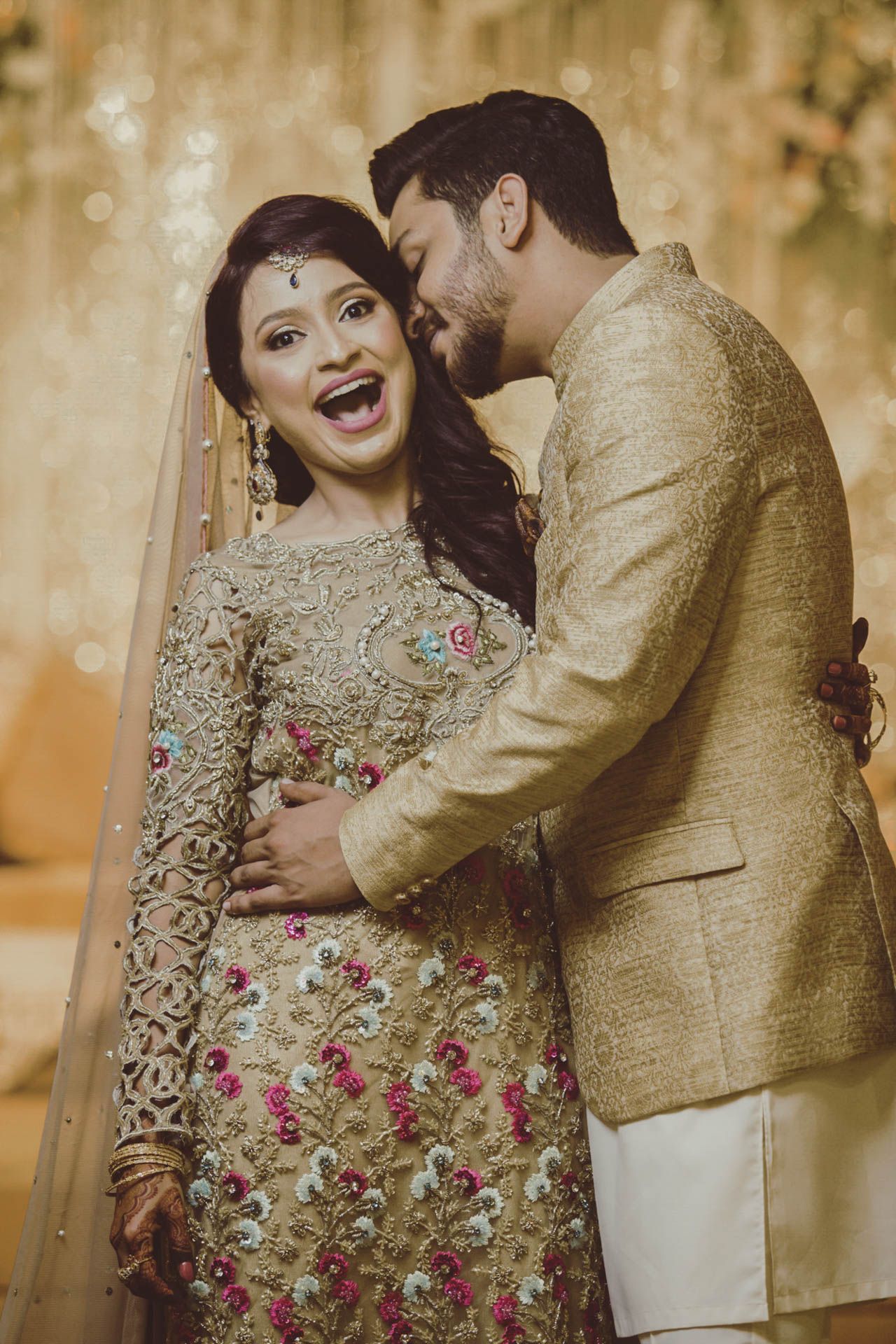 Karachi wedding reception where bride and groom pose in front of a grand floral stage with vintage lighting.