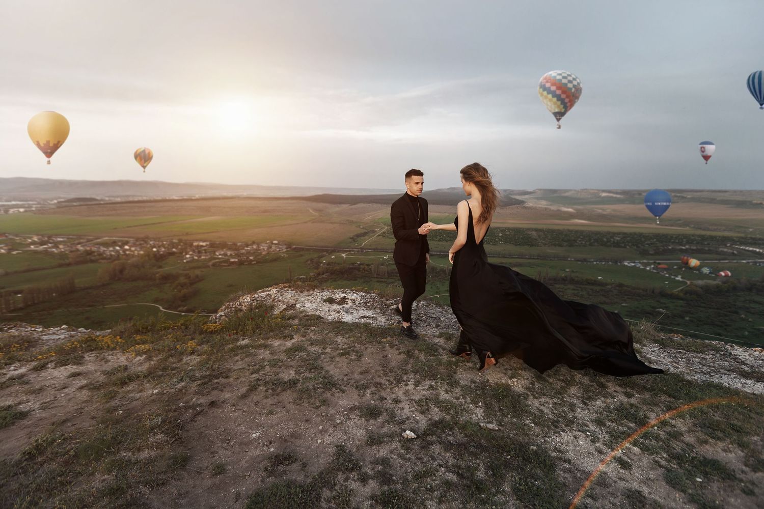 Couple kissing at sunset in Cappadocia, Turkey, with hot air balloons rising in the background — a true fairy-tale moment.