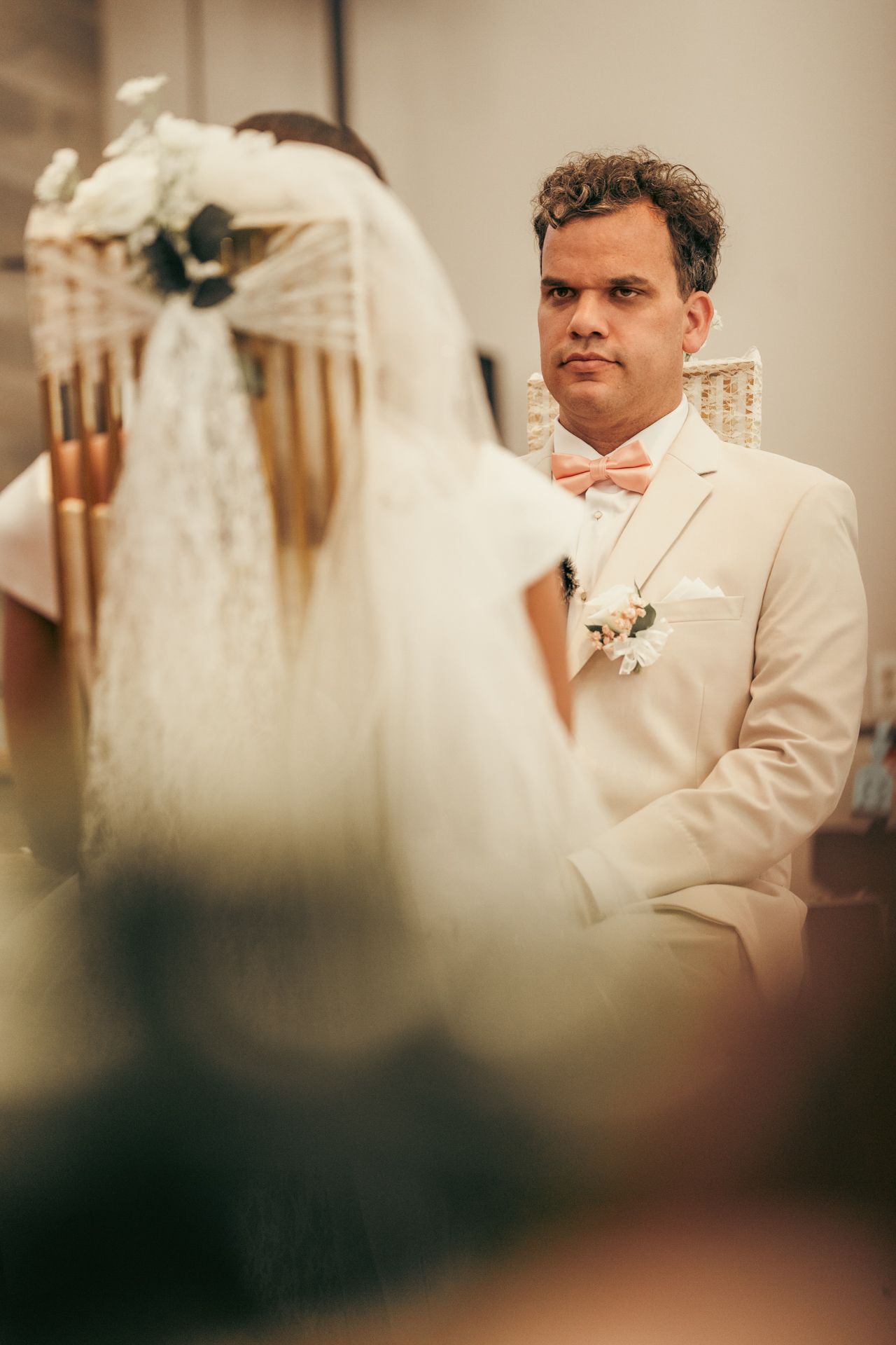 Bride and groom posed in front of the altar with glowing candles and floral arrangements.
