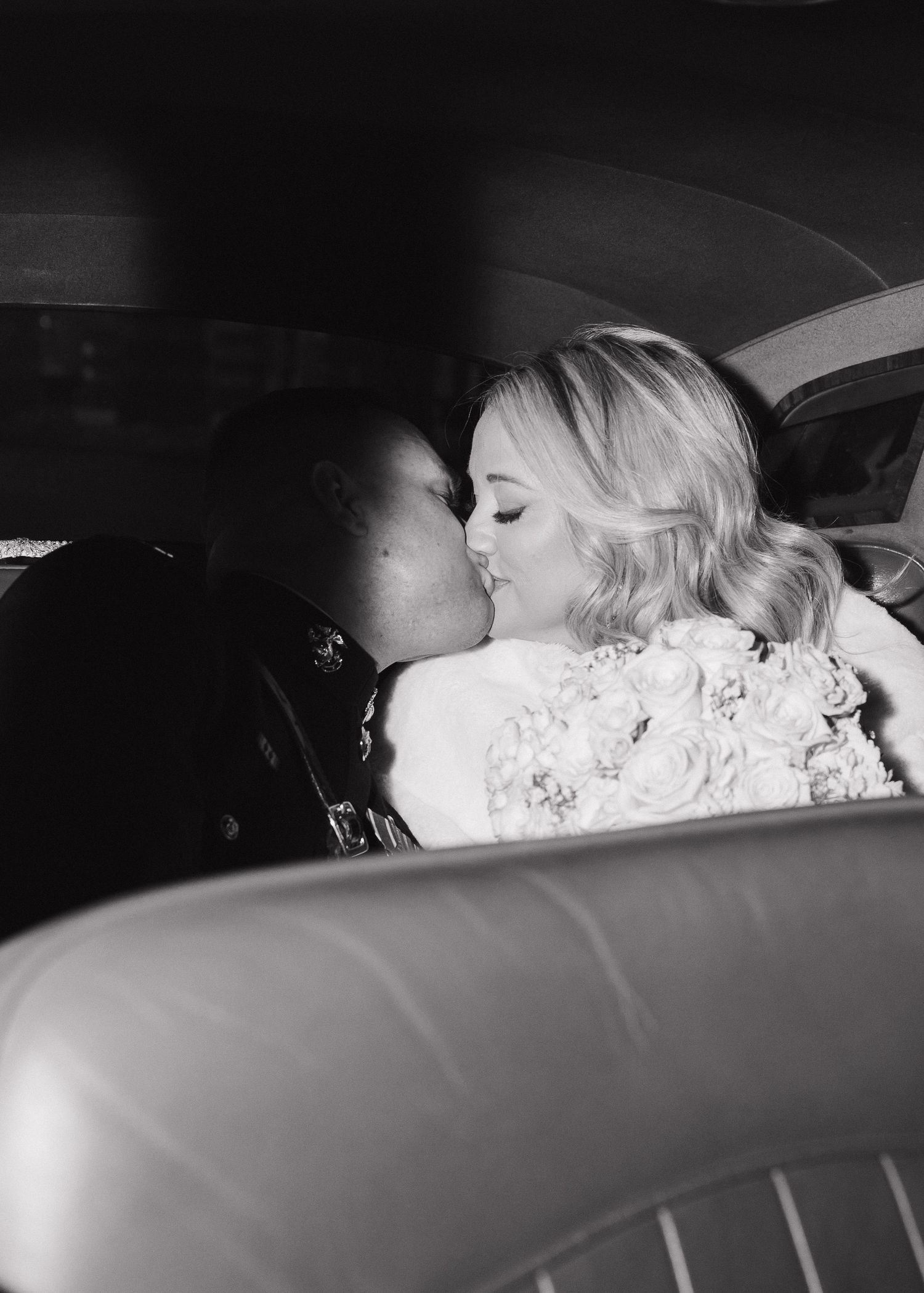 Black and white romantic photo of bride and groom sharing a kiss inside a vintage wedding getaway car. Vintage Car.